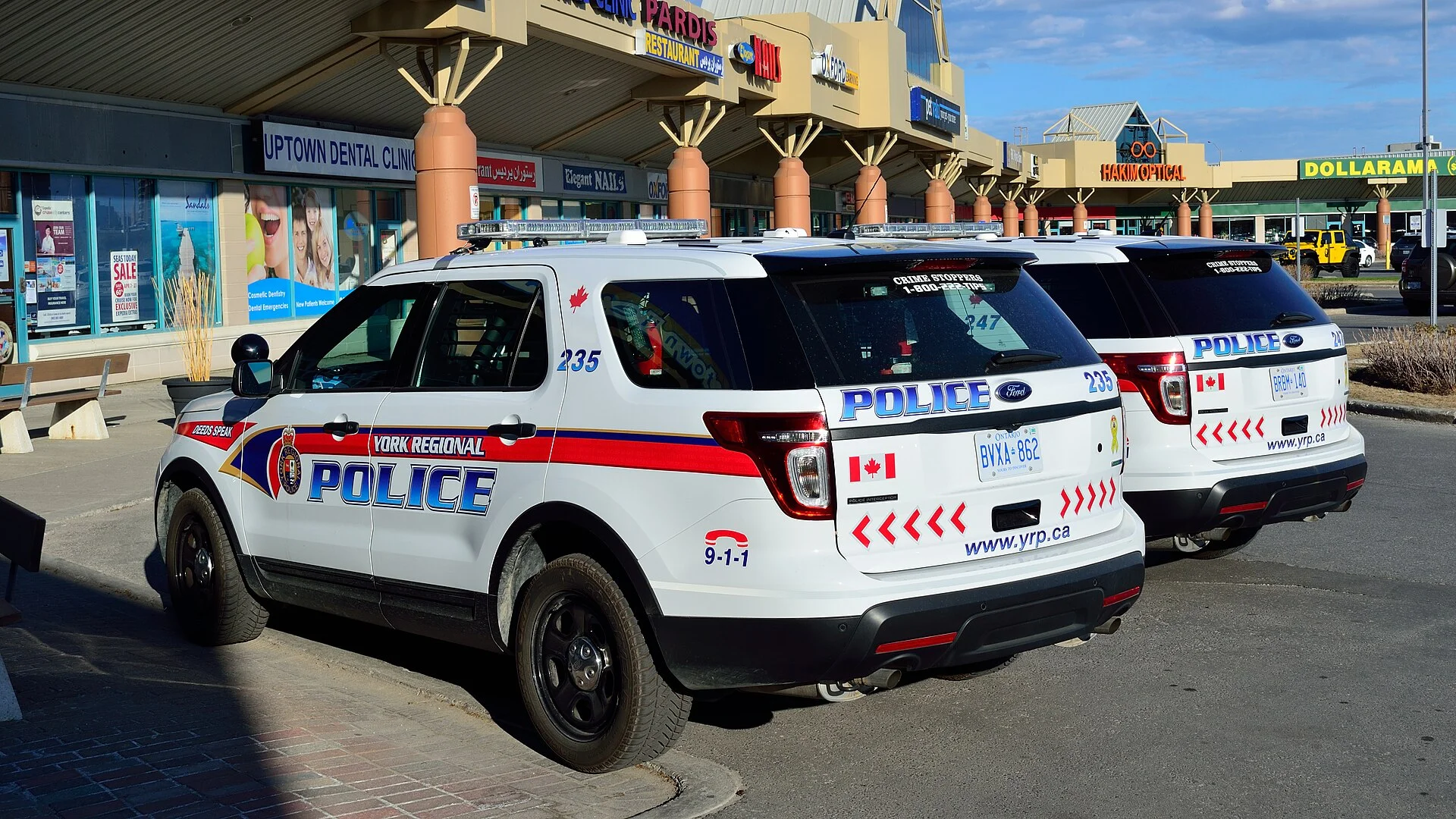 Two York Regional Police SUVs parked outside a suburban shopping plaza on a sunny day