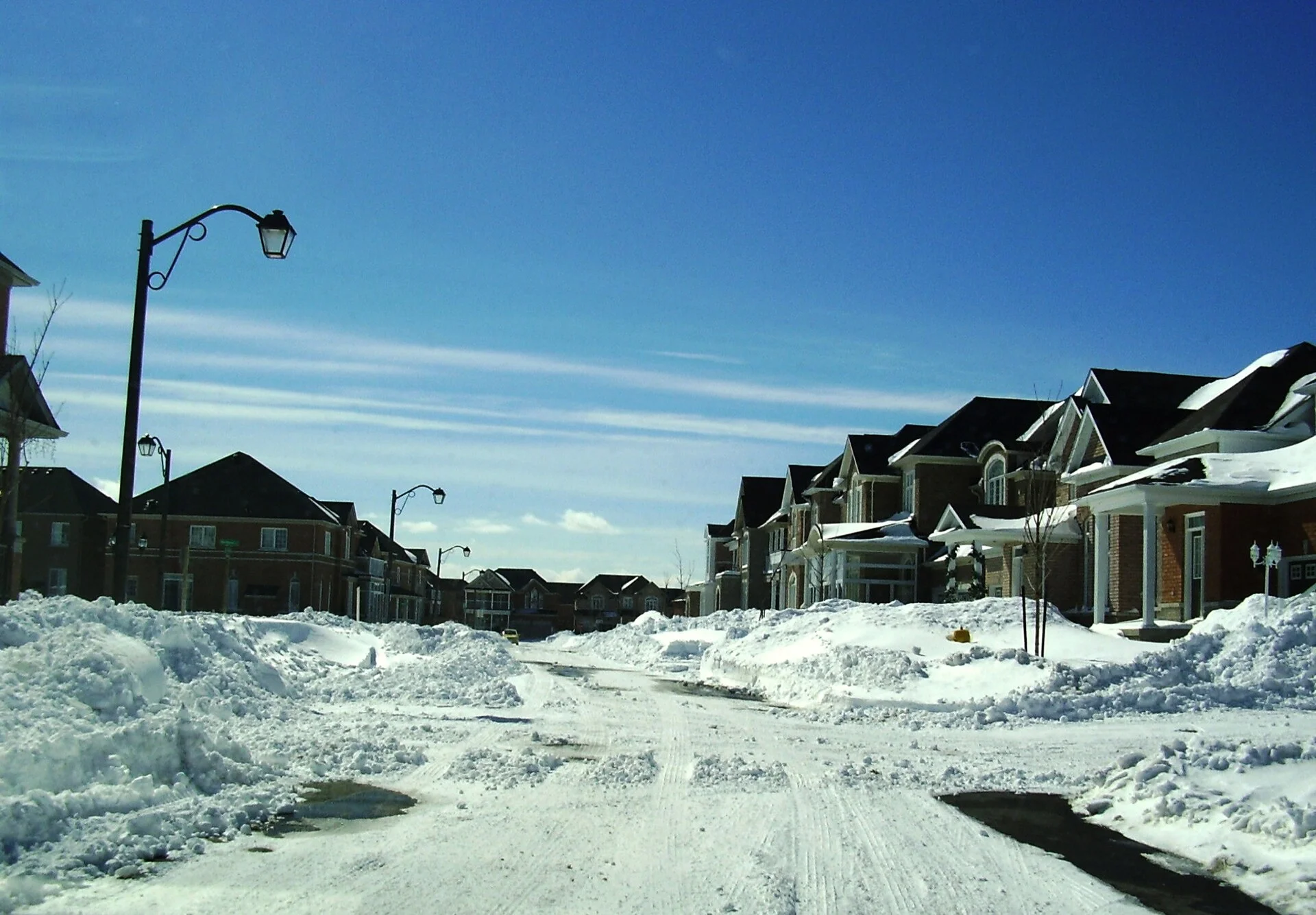 A snow-covered residential street in Markham lined with high snowbanks after a storm