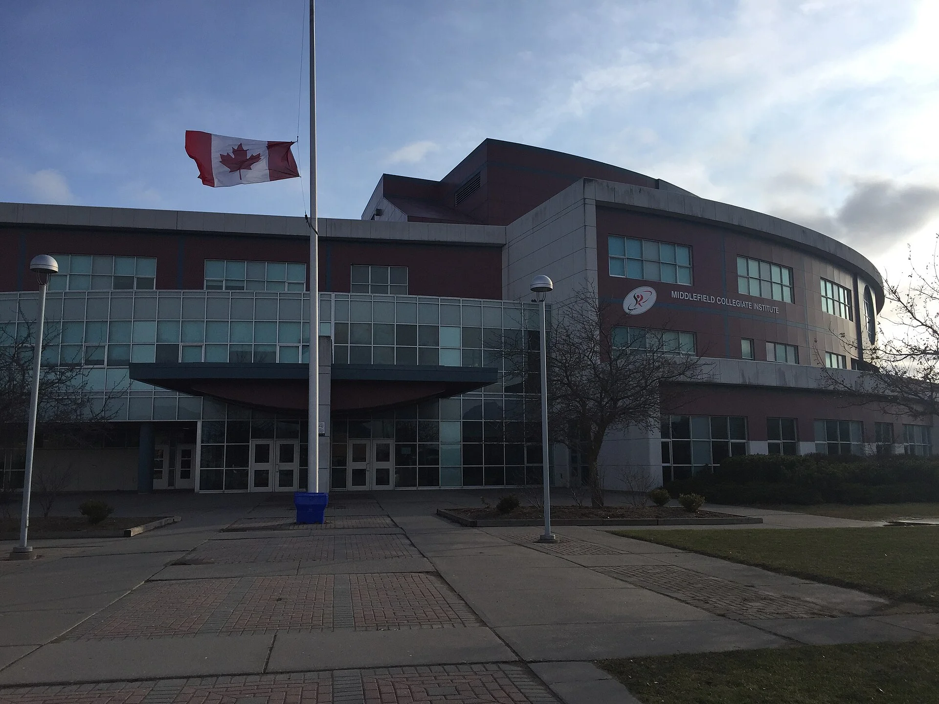 The curved front of Middlefield Collegiate Institute in Markham, with a Canadian flag on a pole by the entrance