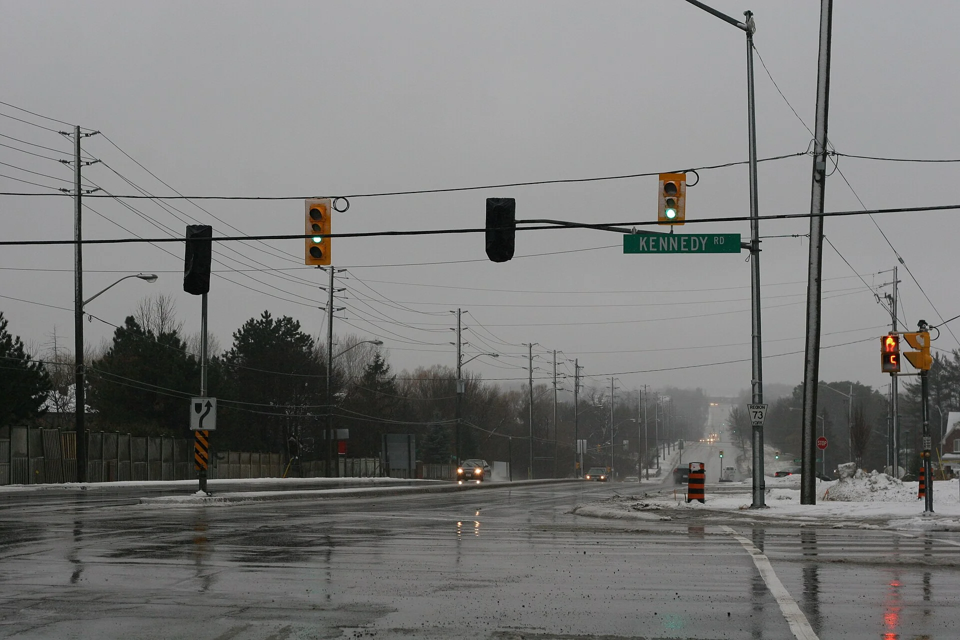 Traffic signals over a wet, slushy 16th Avenue at Kennedy Road in Markham on a grey February day