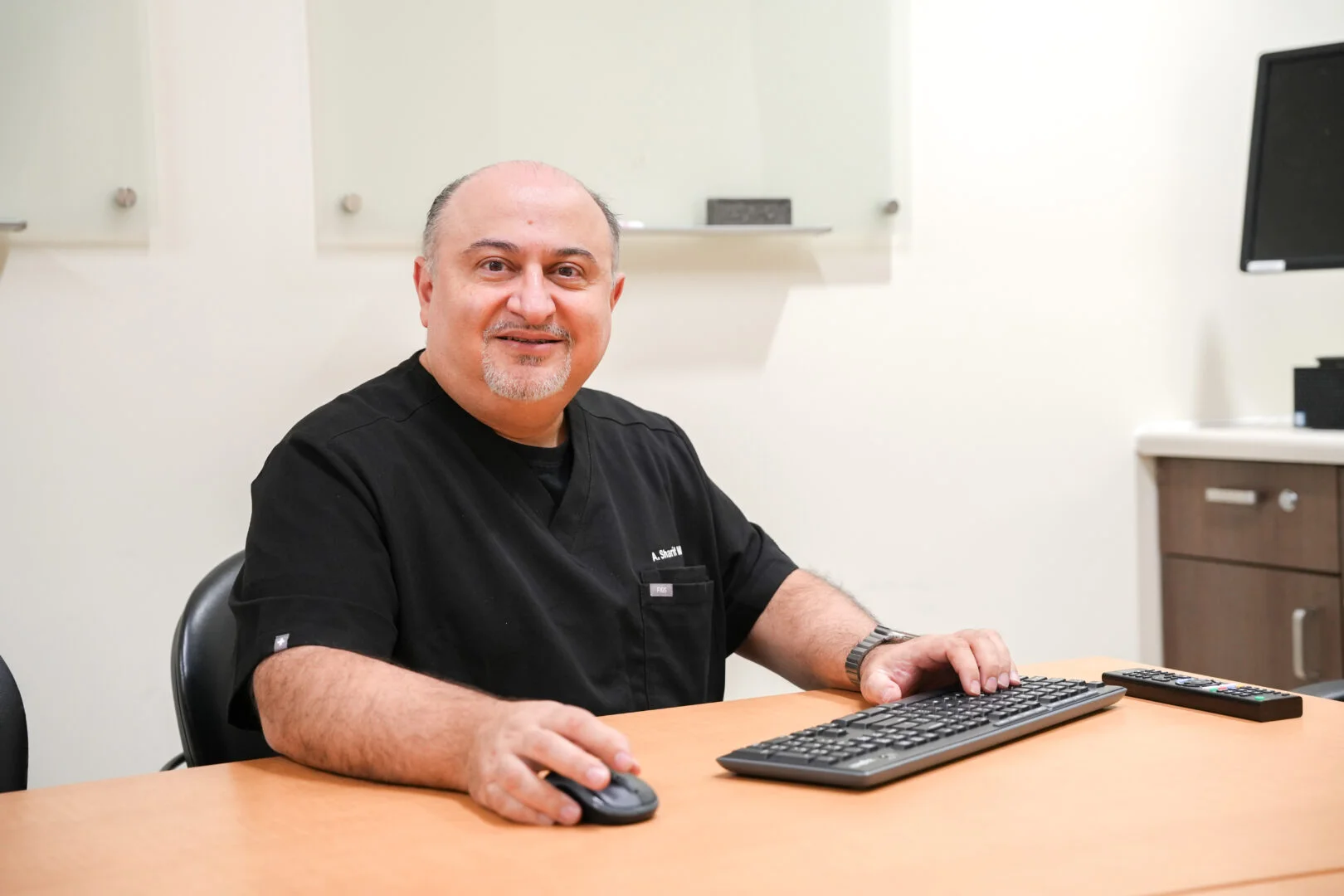 Dr. Anoosh Sharif, a radiologist at Markham Stouffville Hospital, seated at a desk with a keyboard and mouse