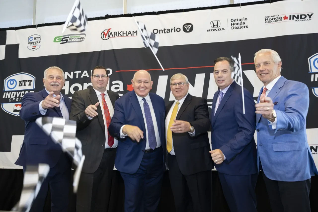 Officials wave chequered flags in front of an Ontario Honda Dealers Indy backdrop at the September 2025 announcement of the race's move to Markham