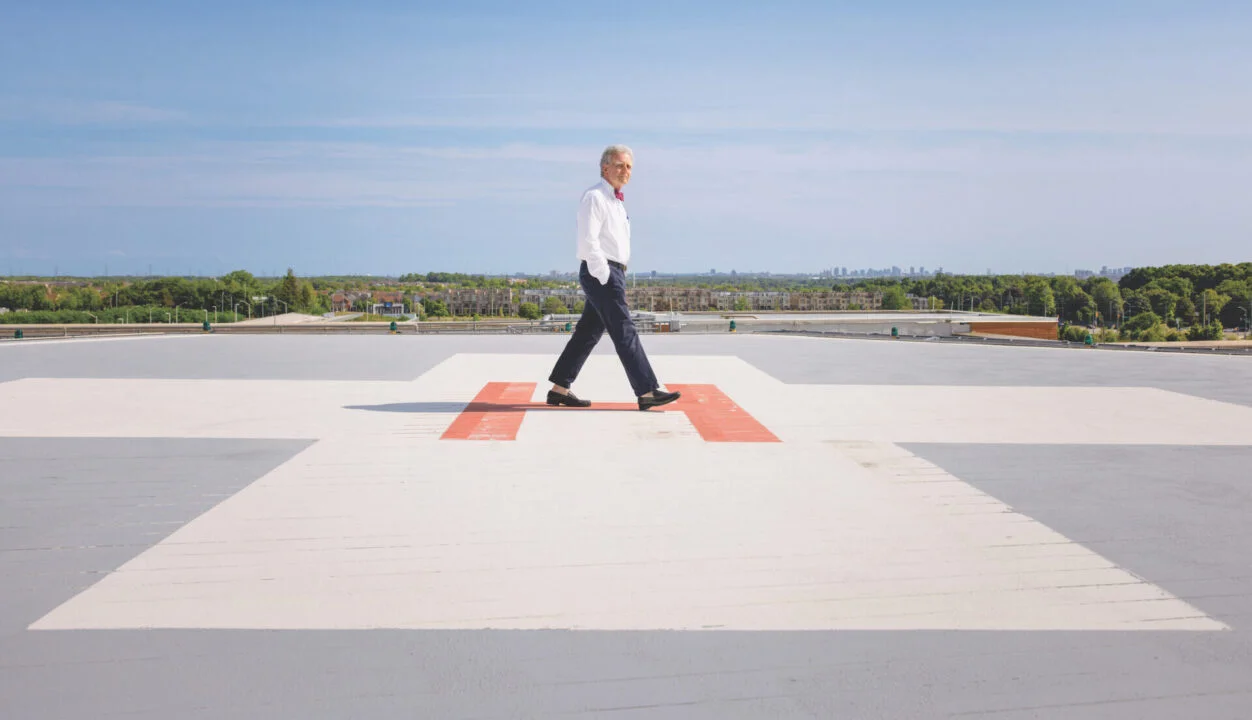 Dr. Henry Solow walks across a rooftop helicopter landing pad on a sunny day