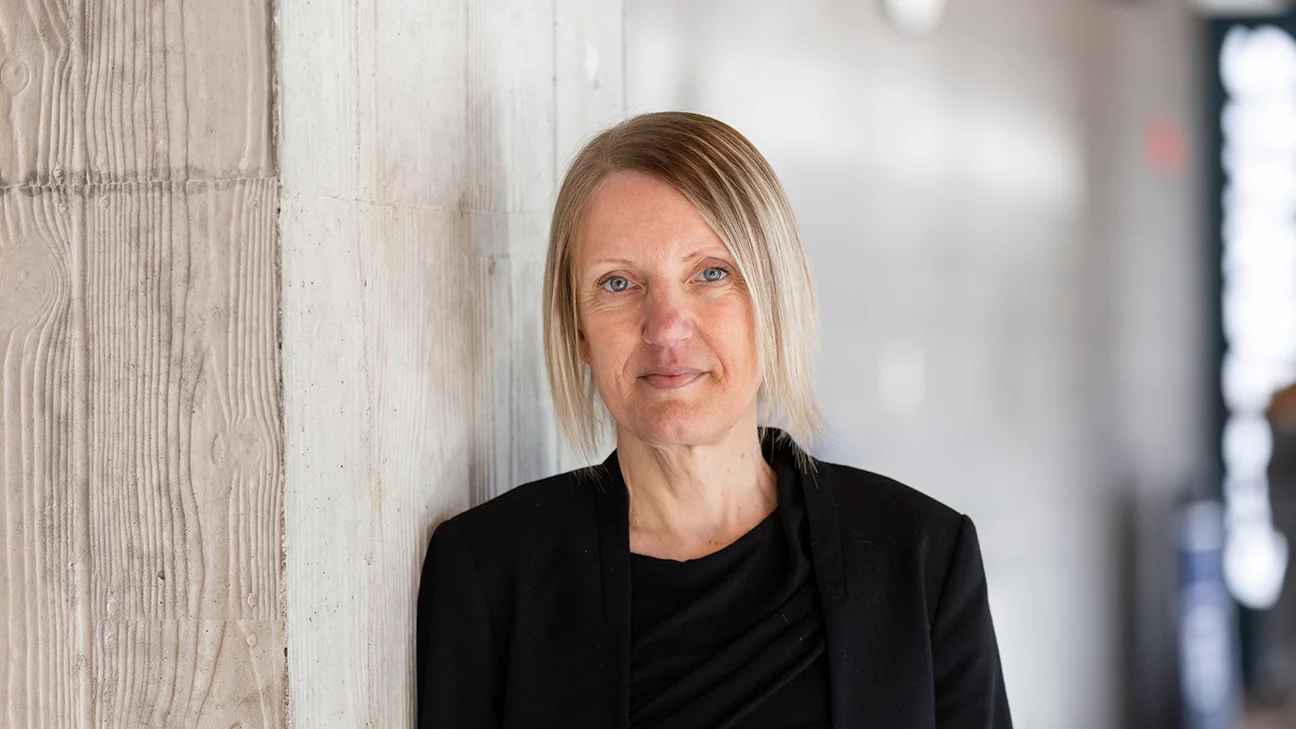 Psychology professor Emily Impett leaning against a concrete wall on the University of Toronto Mississauga campus