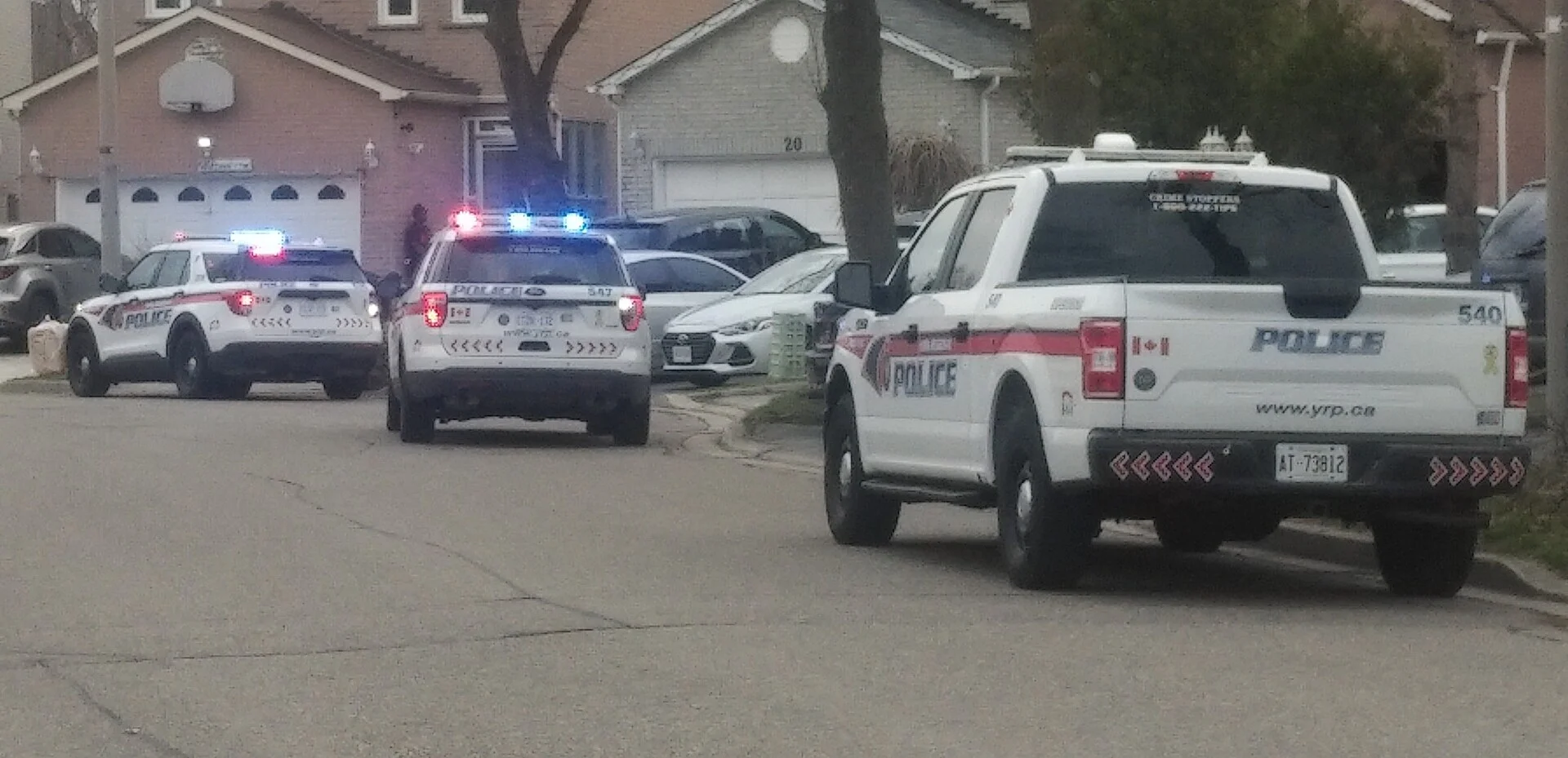 York Regional Police cruisers and a pickup truck with emergency lights on, stopped along a suburban residential street