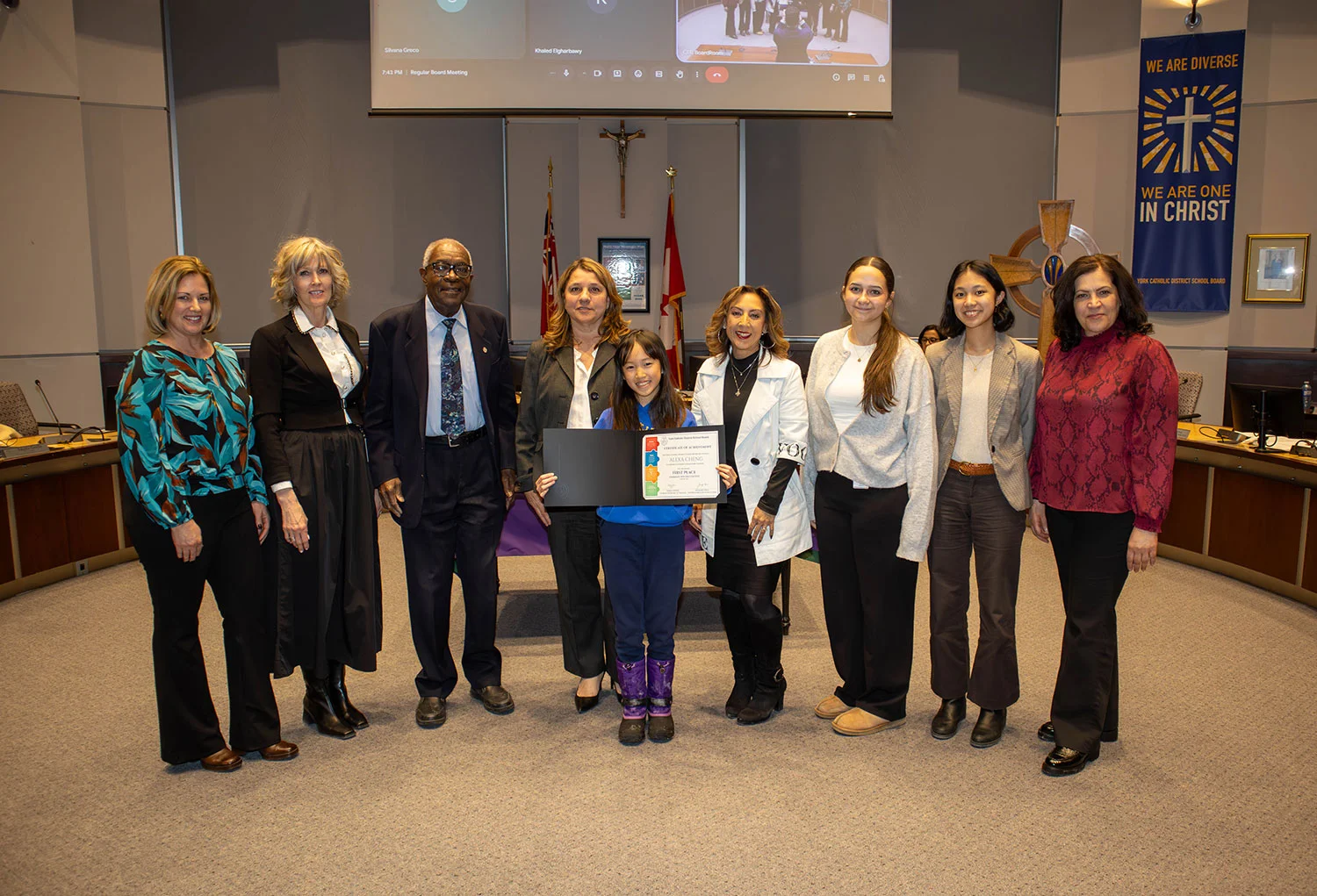 A St. Edward Catholic Elementary School student holds her certificate while standing with York Catholic trustees and staff in the board room