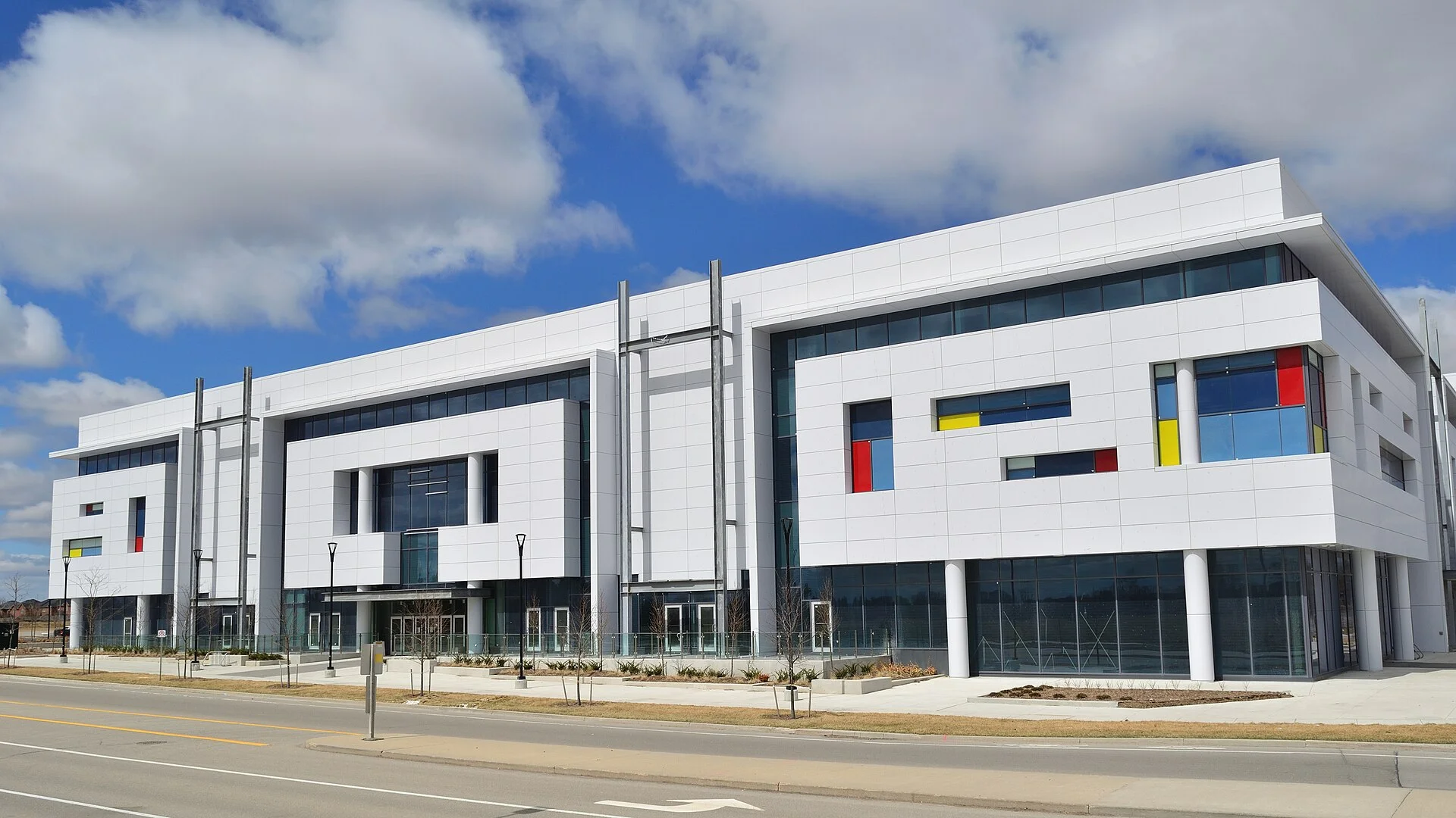 The white exterior of King Square Shopping Centre in Markham, with tall windows and coloured glass panels, under a partly cloudy sky