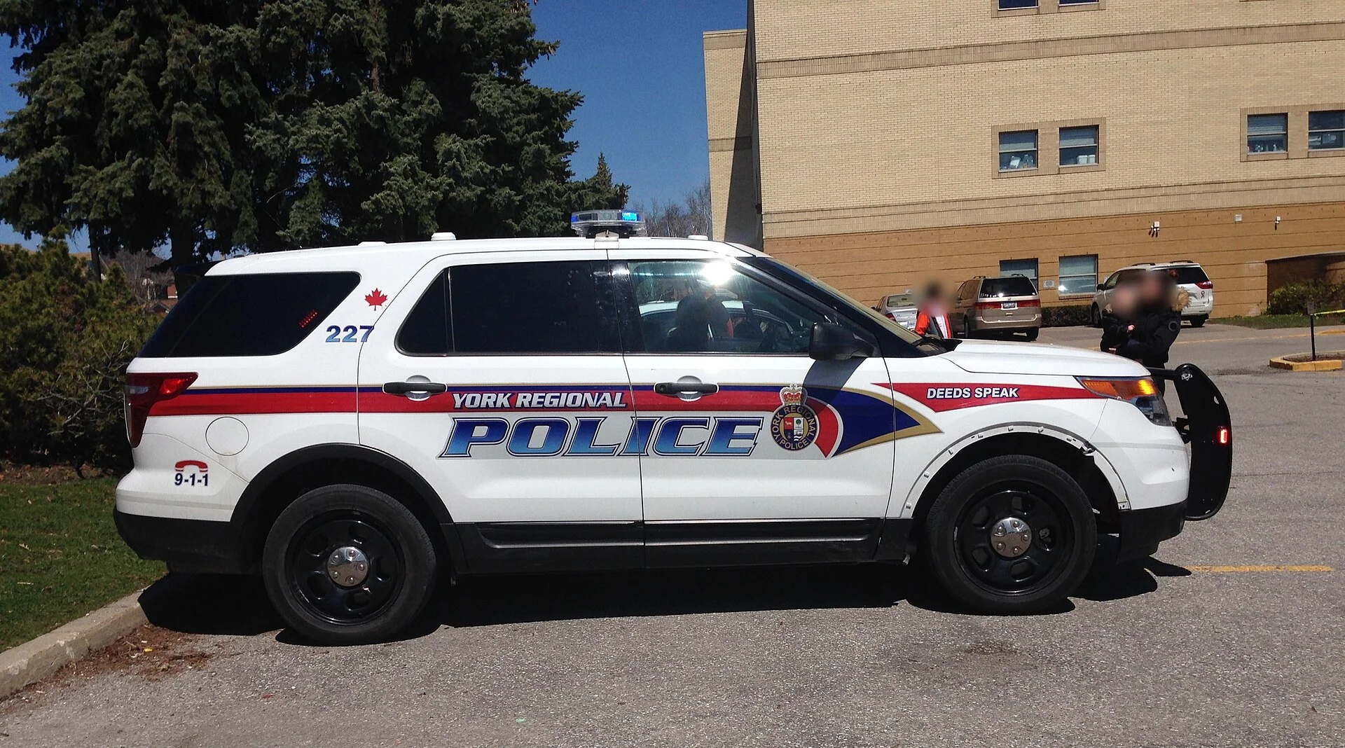 A white York Regional Police cruiser with red and blue striping parked outside a building