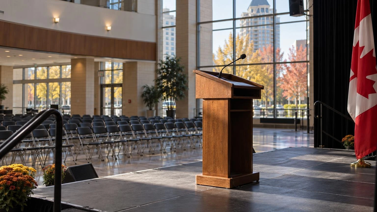 A close-up of a wooden podium and a microphone in a community centre hall.