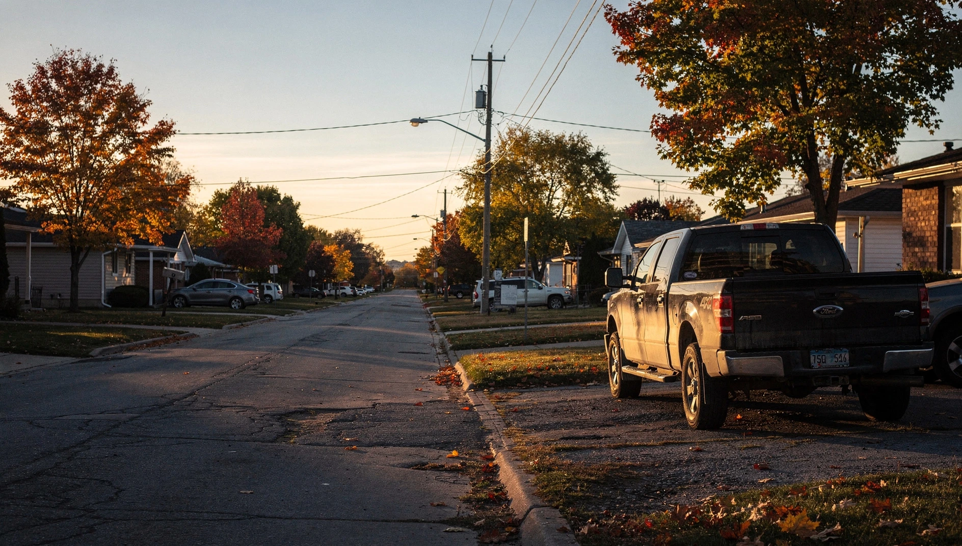 A residential street in Niagara Falls at dusk with parked vehicles and streetlights.