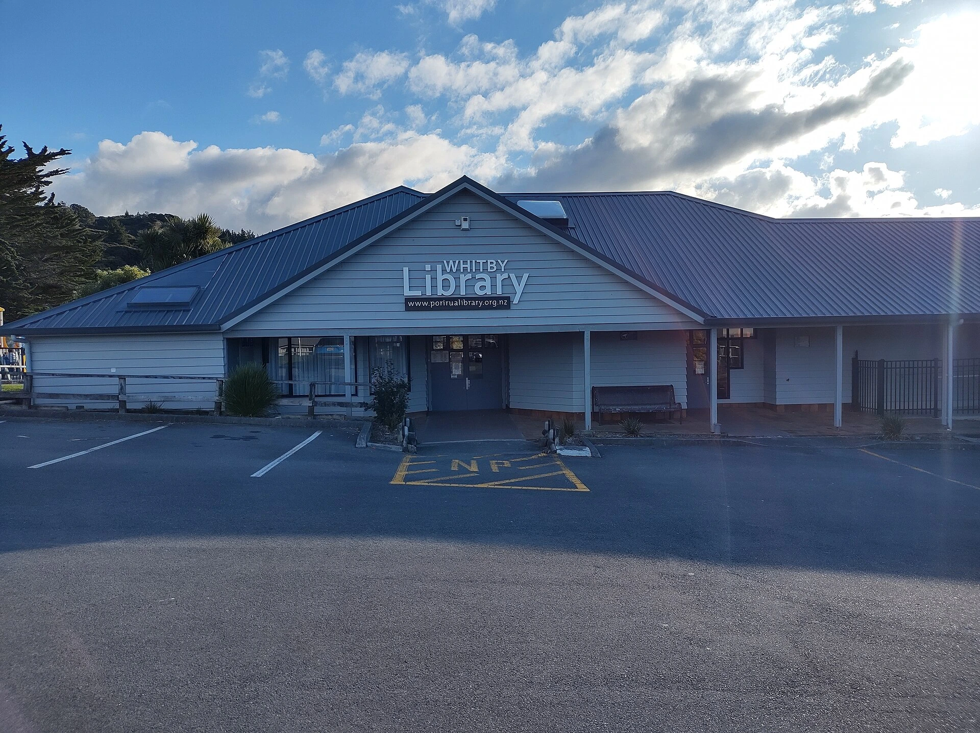 A public library branch in autumn, with orange and red leaves on nearby trees.