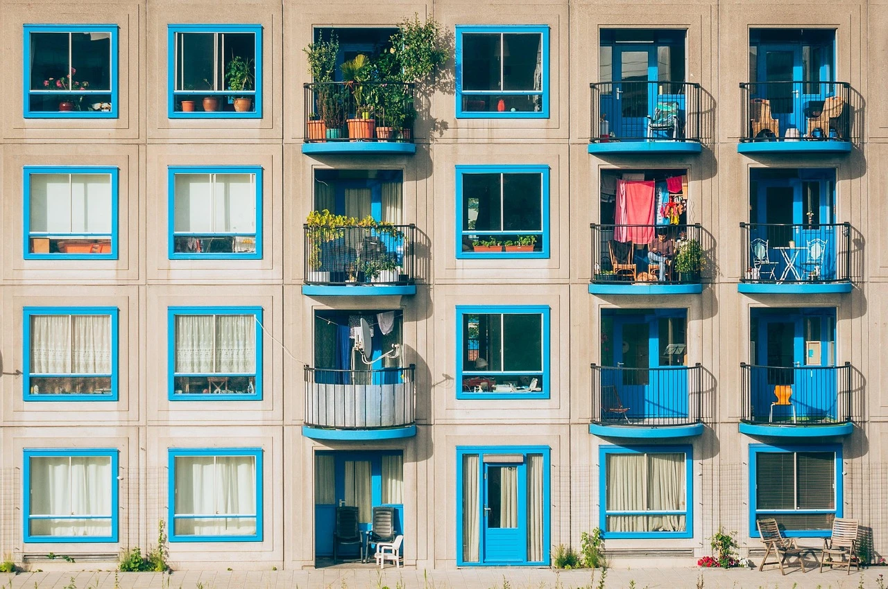 A rental apartment building with balconies on a tree-lined residential street in Mississauga on a summer day.