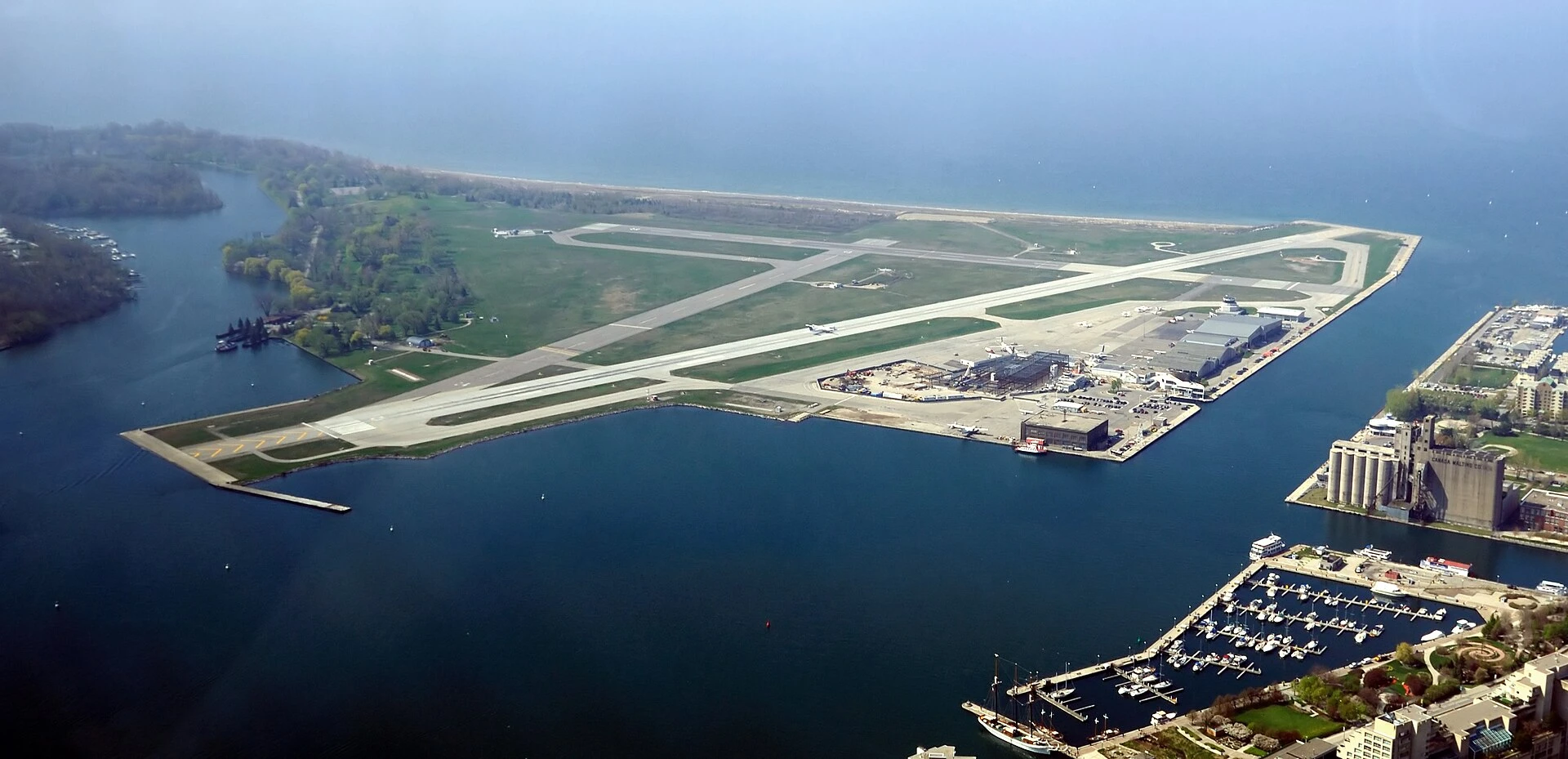 Billy Bishop Toronto City Airport seen from the Toronto waterfront in summer, with the downtown skyline behind it.