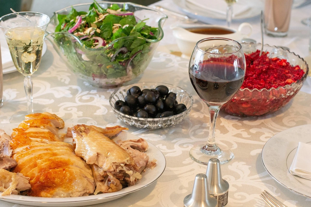 A school gymnasium decorated for autumn with long tables set for a community Thanksgiving lunch, turkey dinners on a serving table and handmade centrepieces