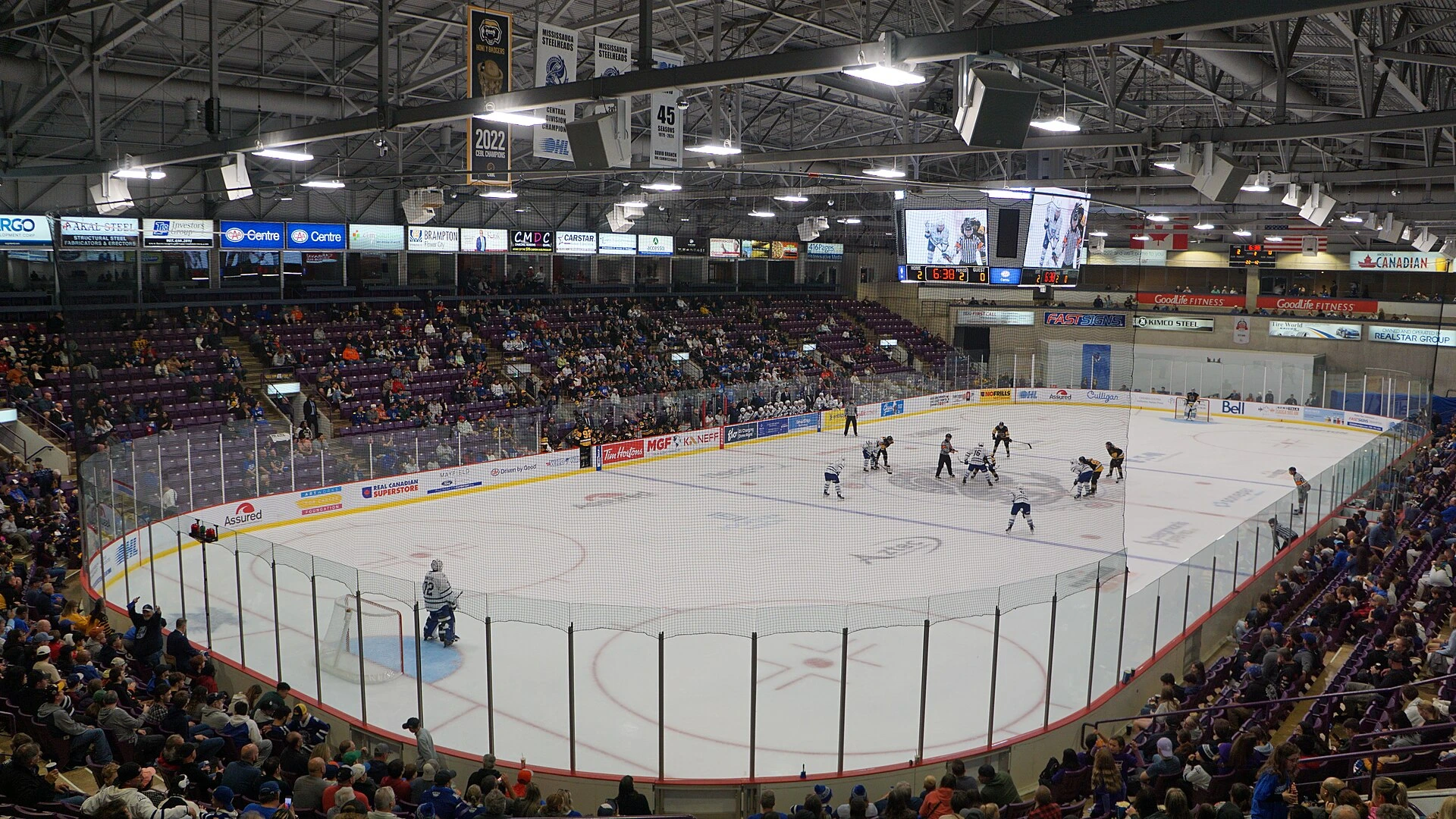 An empty hockey rink inside an Ontario arena, with boards, glass and stands visible under arena lights.