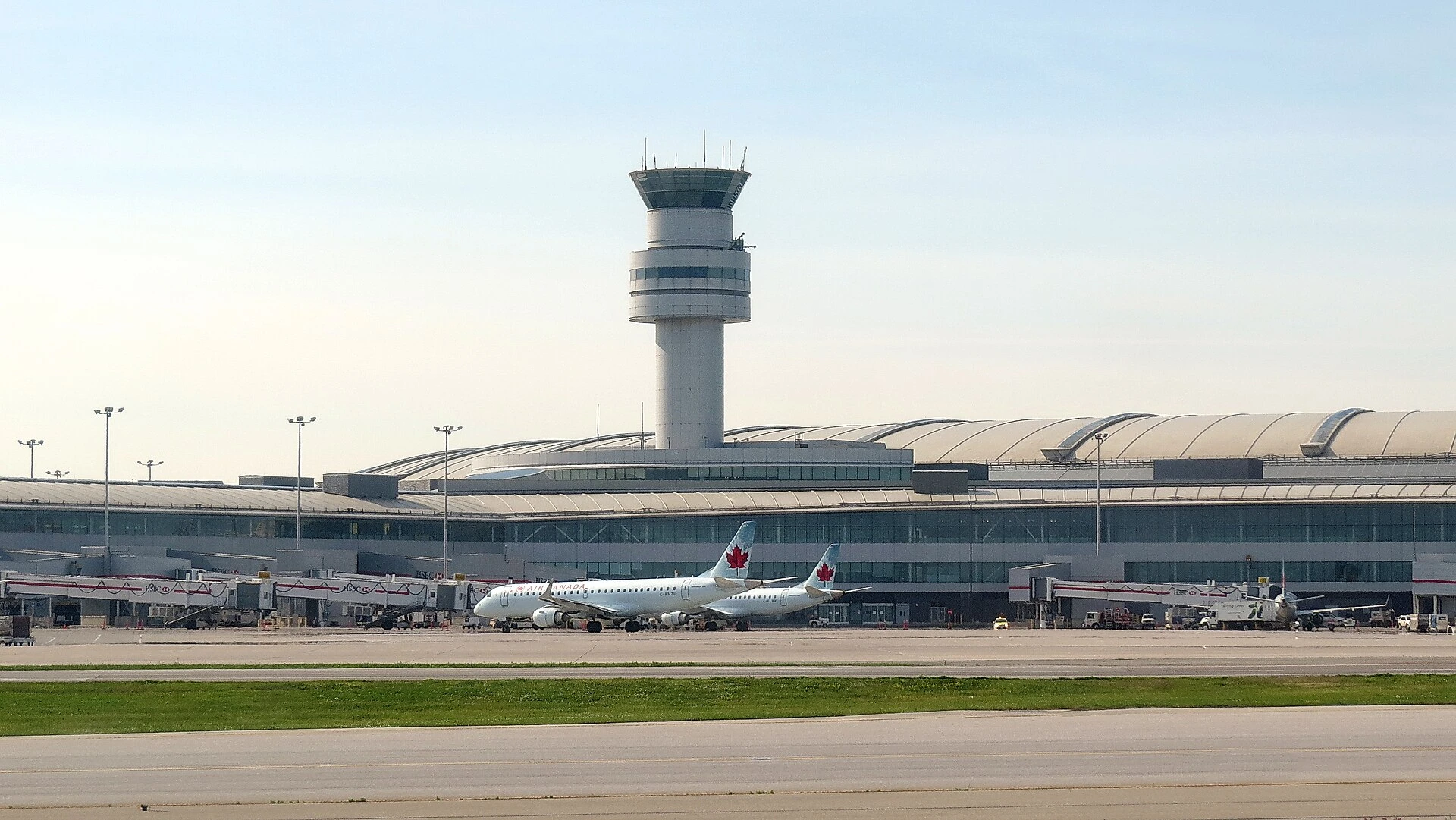 An air traffic control tower at a large Ontario airport with an airliner on the tarmac below.