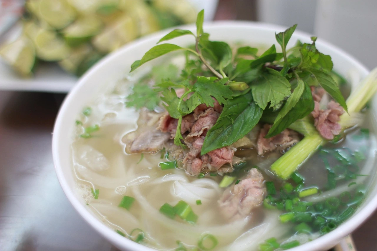 An illustration of a fast-casual restaurant counter with bowls of pho and garnish toppings laid out.