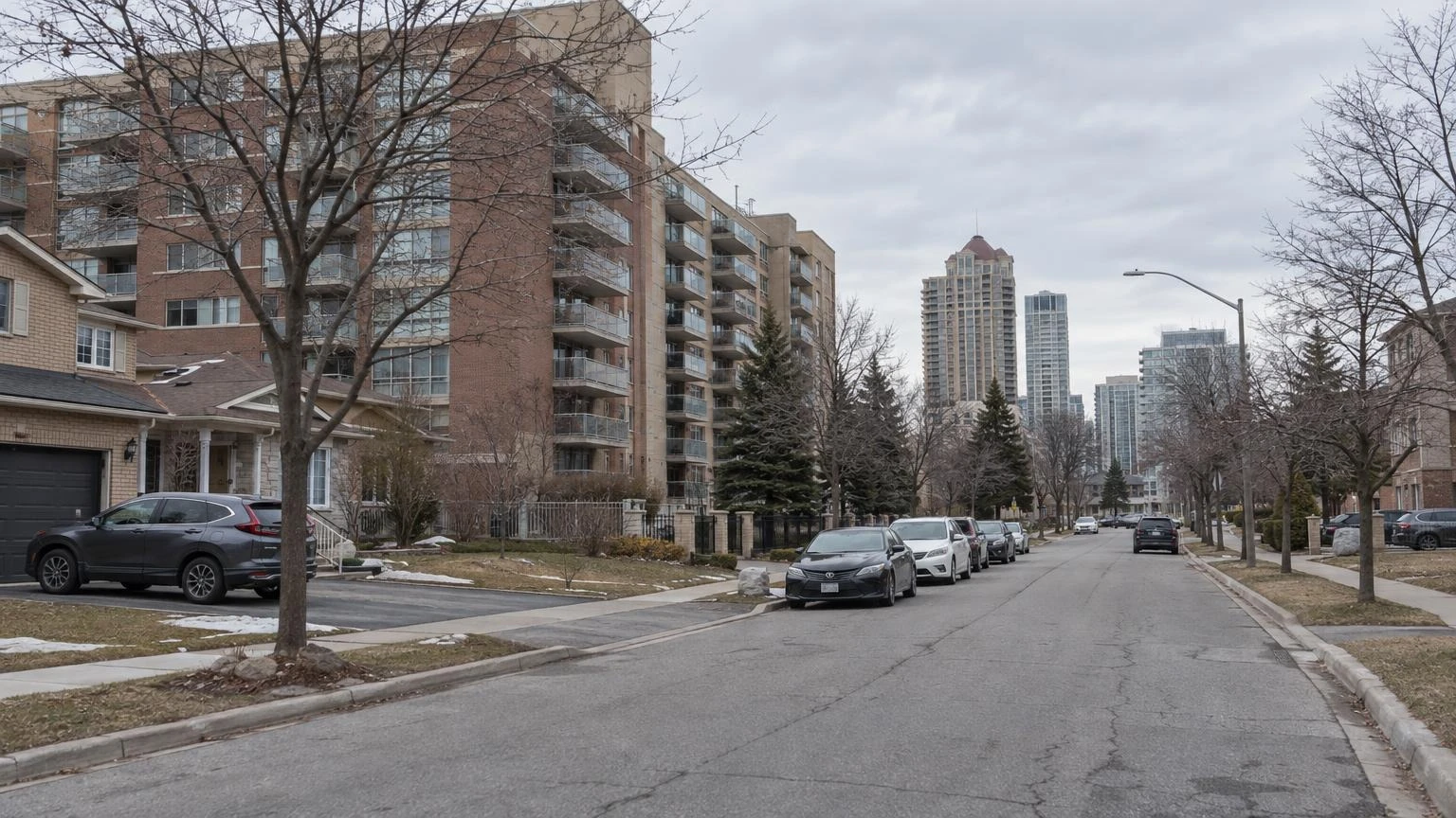 A residential street in Mississauga with suburban apartment buildings and houses under a cloudy March sky.