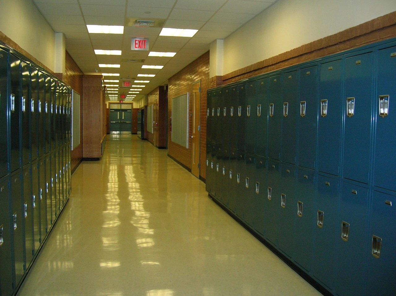 Parents and students walk toward a brick high school entrance on an autumn evening.