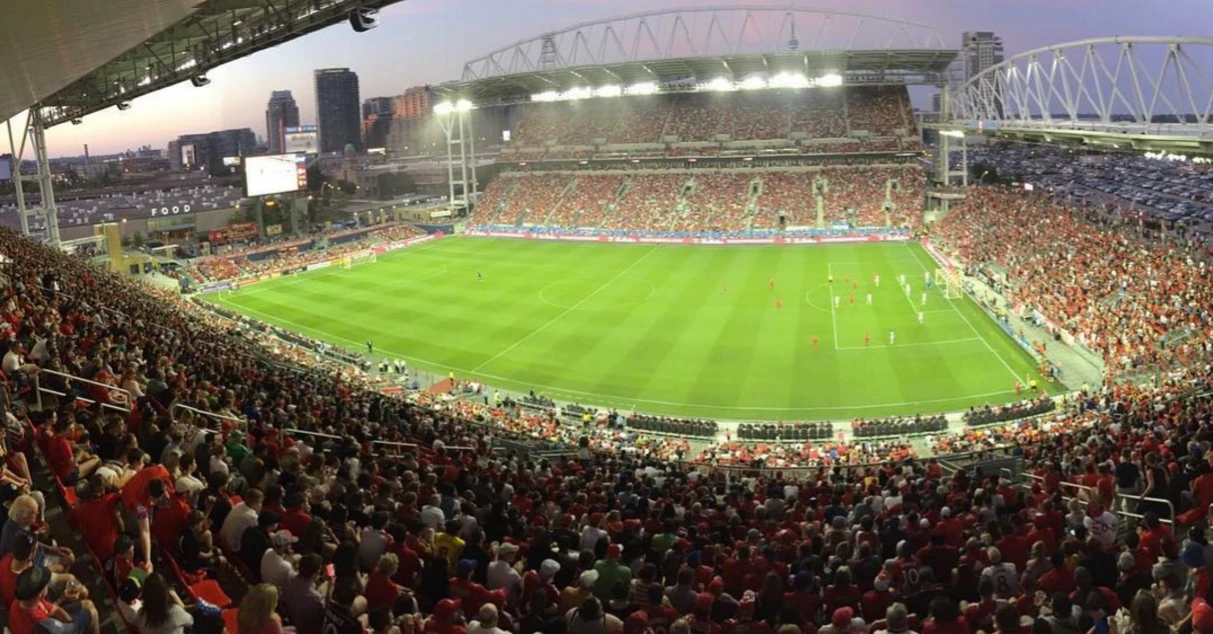An empty stadium pitch and grandstands under a summer sky, representing a soccer match venue in Toronto.