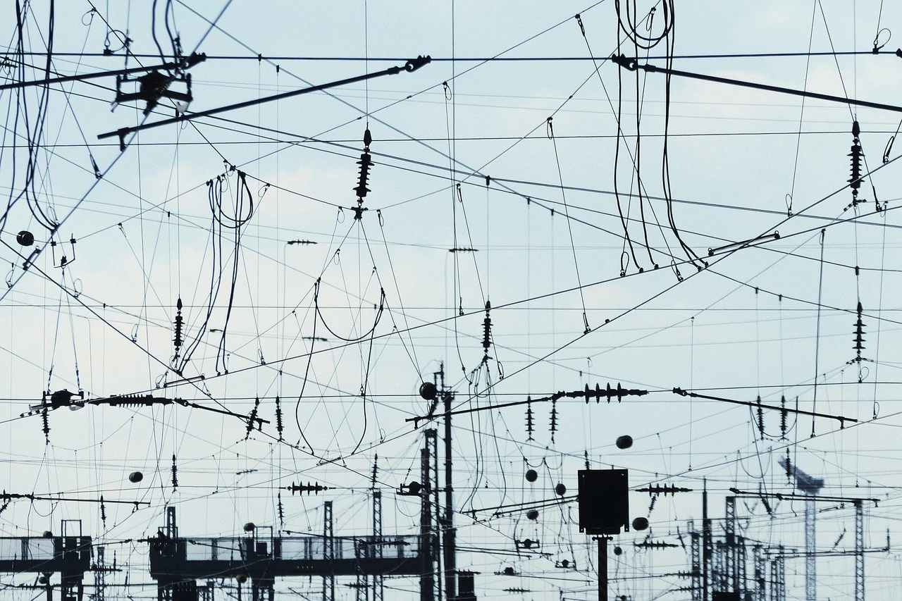 Illustration of electrical equipment behind a fence at a transformer station in a spring setting.