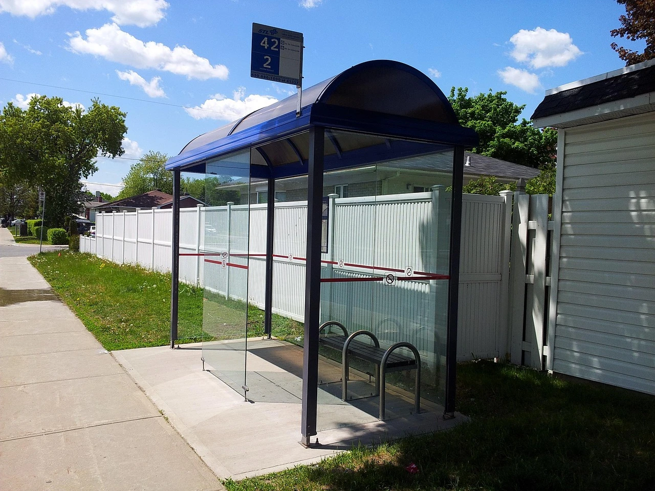 Illustration of a transit bus beside a sidewalk and curb ramp on a leafy suburban street.