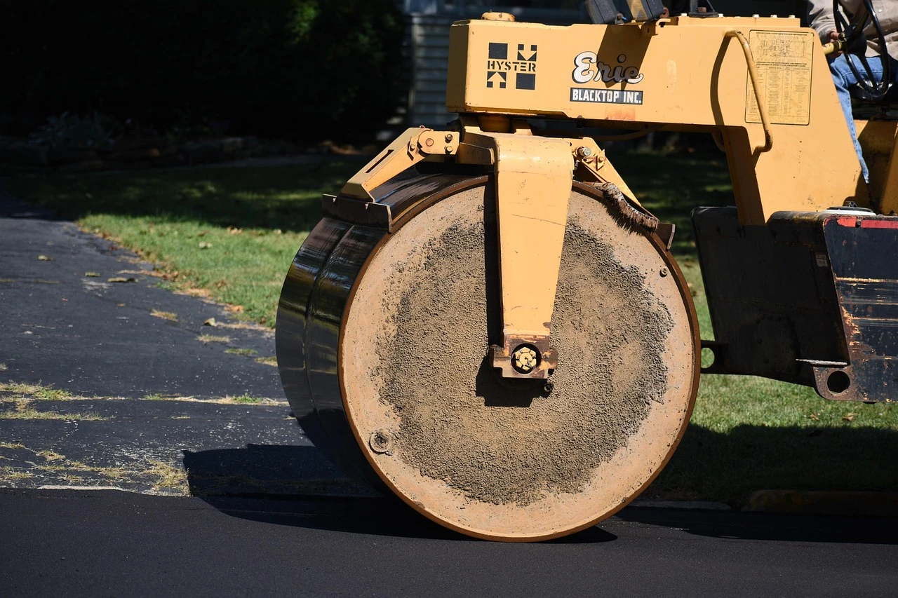 An illustration of road resurfacing work on a suburban road with construction cones and paving equipment.