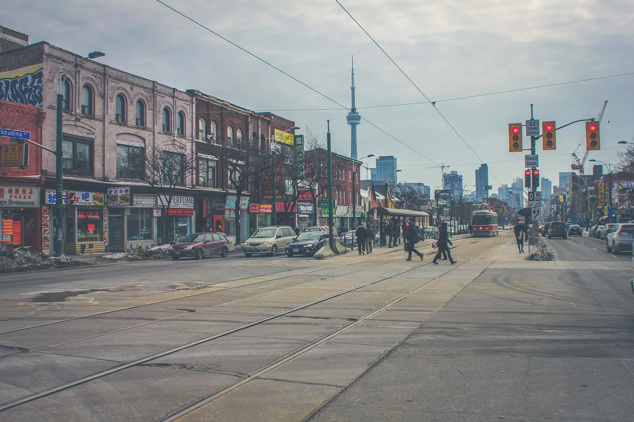 A Toronto streetcar on a downtown street with summer greenery and traffic.