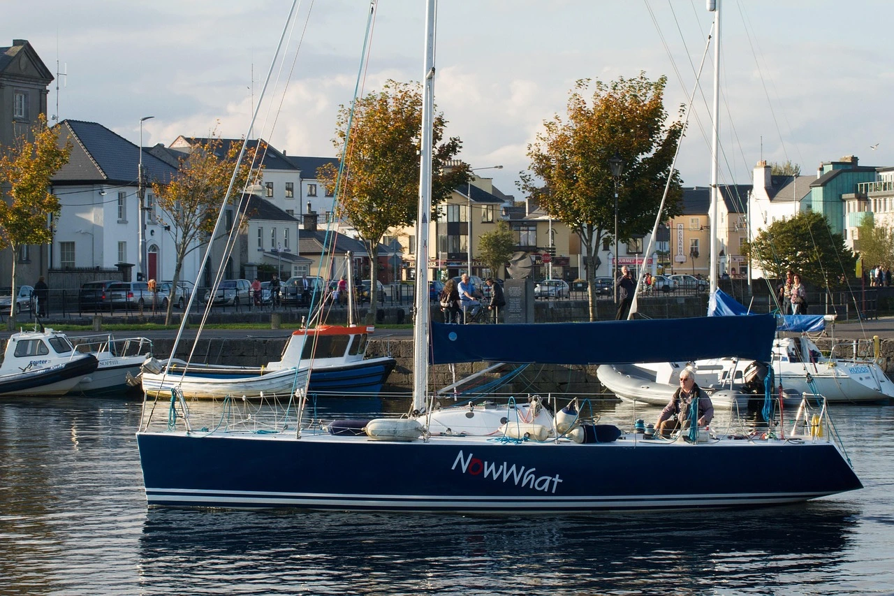 Sailboats moored at a marina in Whitby at golden hour in autumn, with fall-coloured trees along the waterfront.