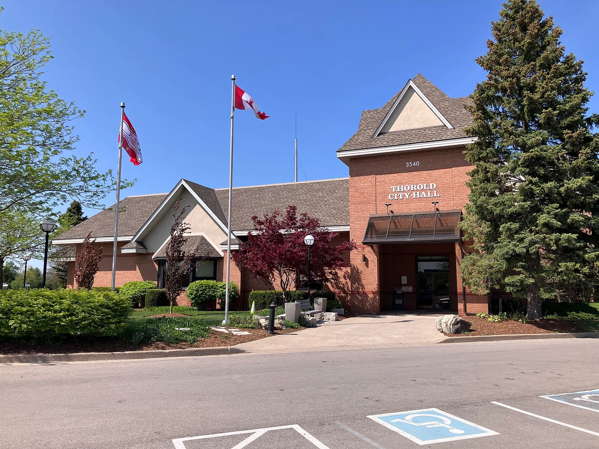 A small Ontario city hall building surrounded by autumn trees and parked cars