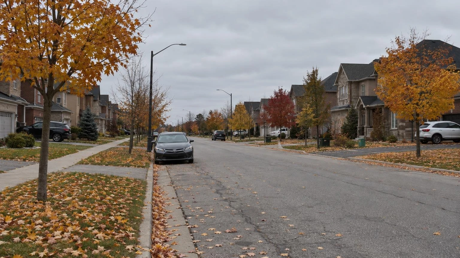 A wide view of a suburban street in Caledon, Ontario, with houses and mature trees under an autumn sky.