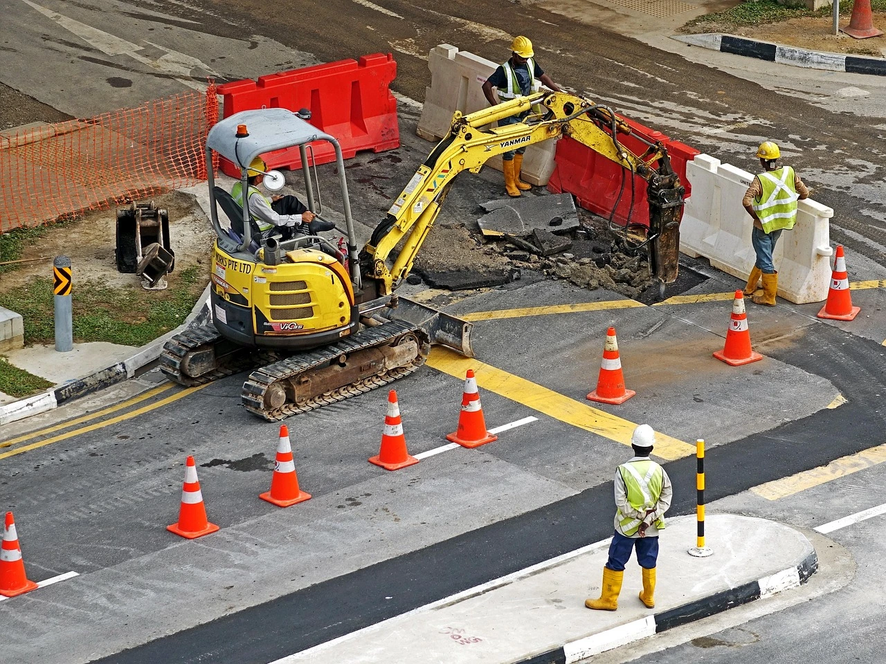 An orange construction cone sits on the edge of an asphalt road next to a concrete sidewalk in Ontario during autumn.