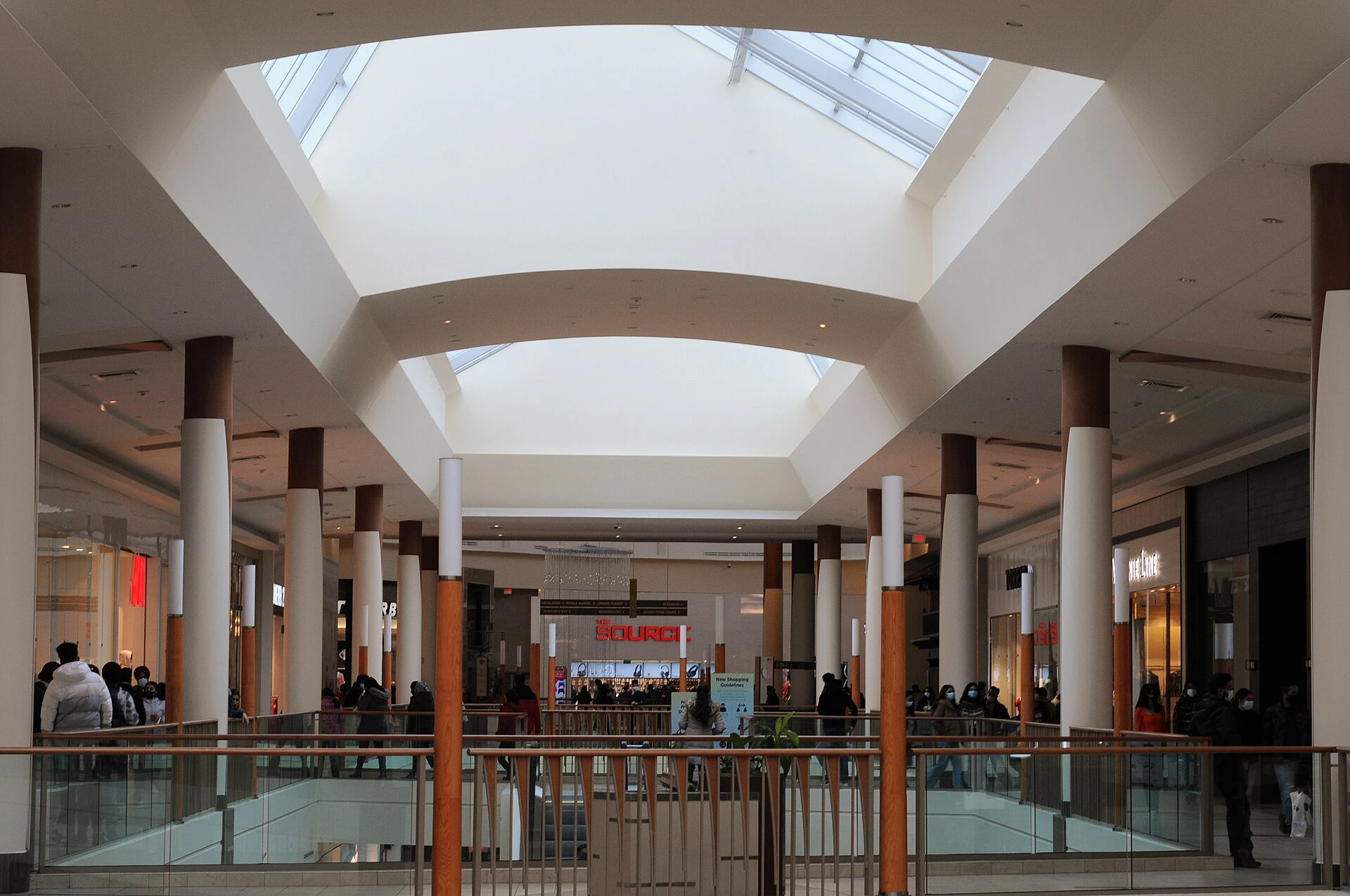 Shoppers walking through the interior concourse of a large enclosed shopping mall.