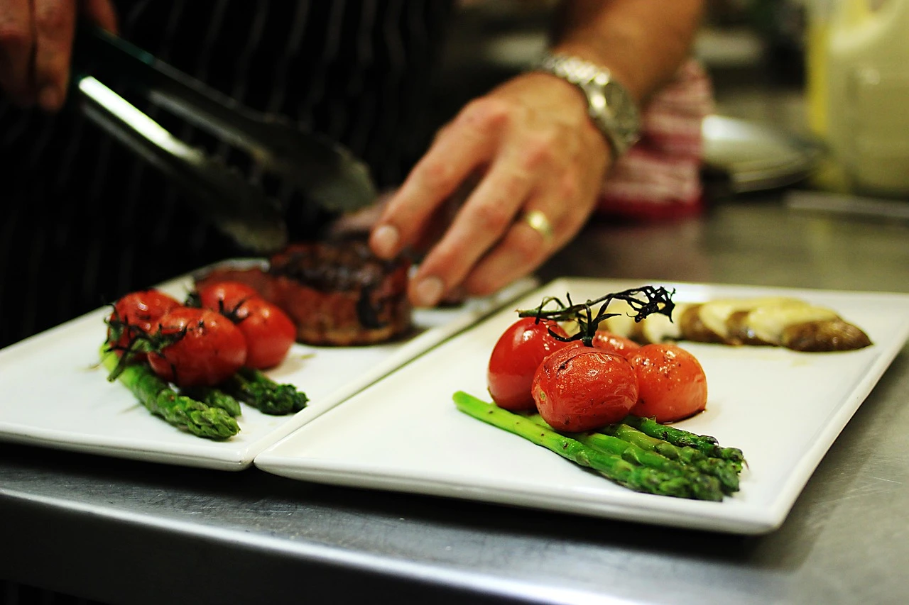 Illustration of meal preparation at stainless-steel work surfaces in a community kitchen.