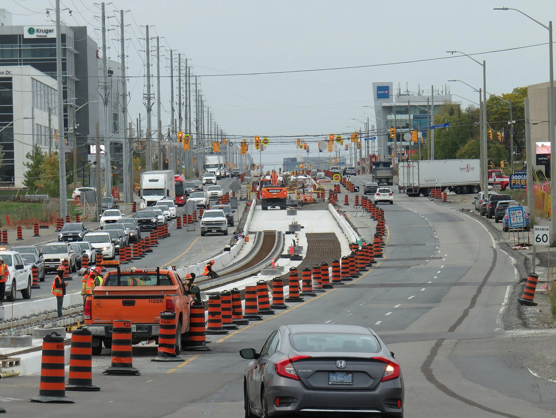 Light-rail tracks and construction equipment along the centre of a wide Mississauga arterial road in summer.