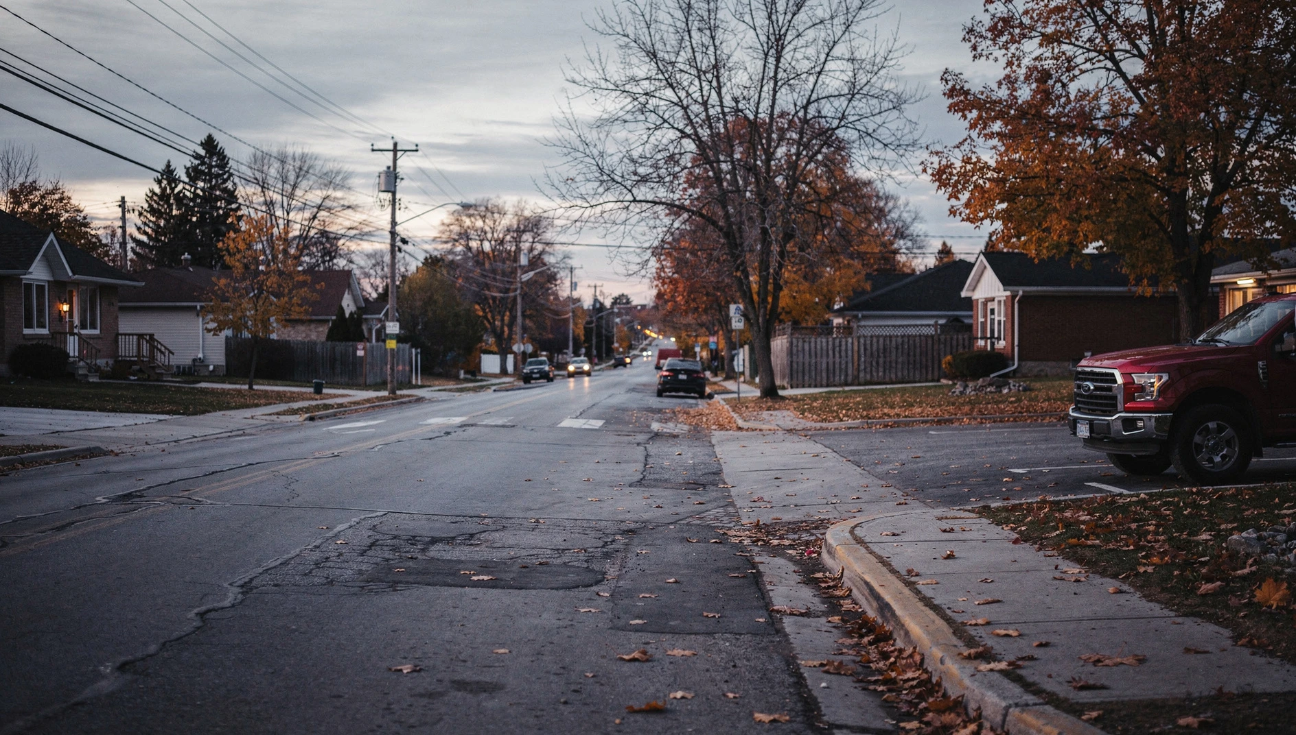 A red pickup truck at a plaza driveway on a tree-lined Niagara Falls street in autumn