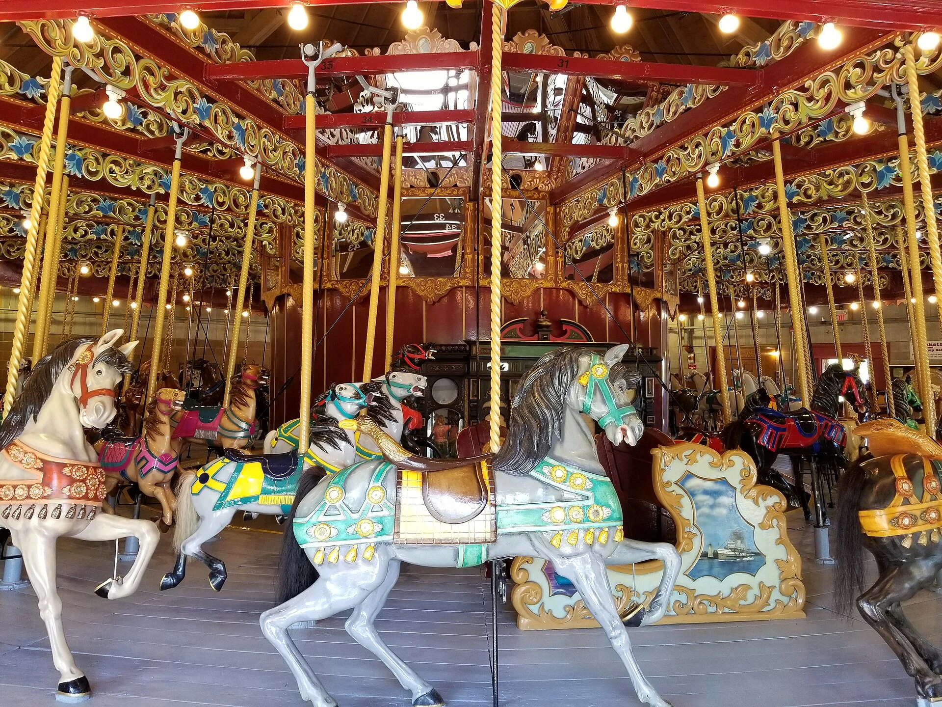 An illuminated vintage carousel at dusk with autumn leaves in the background.