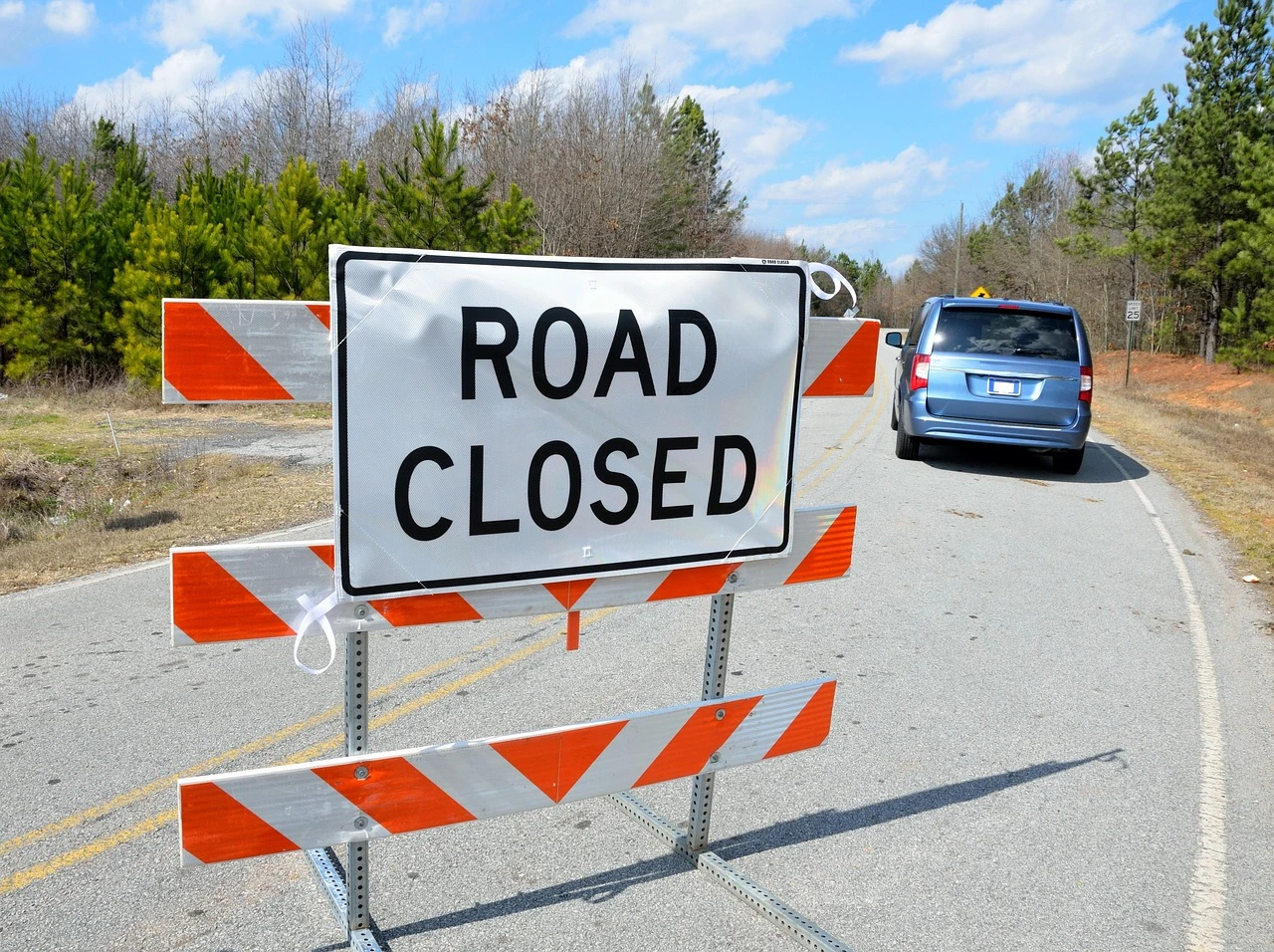 Barricades and detour signs close an intersection at a small Ontario town street in autumn.
