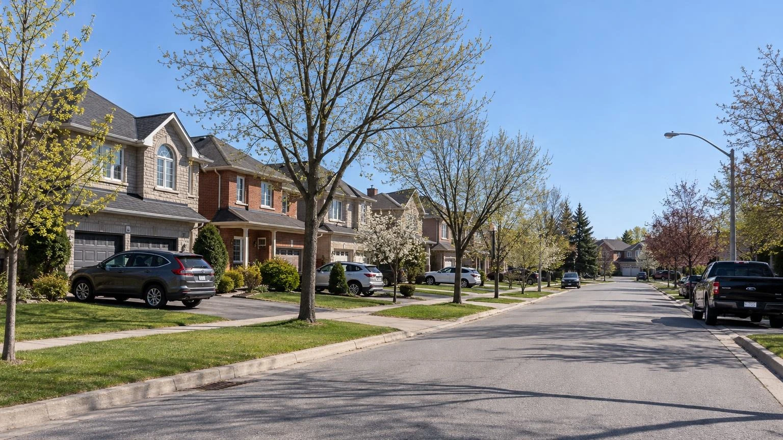 A close-up shot of a residential street in Whitby, Ontario, featuring suburban houses and manicured lawns under a clear spring sky.