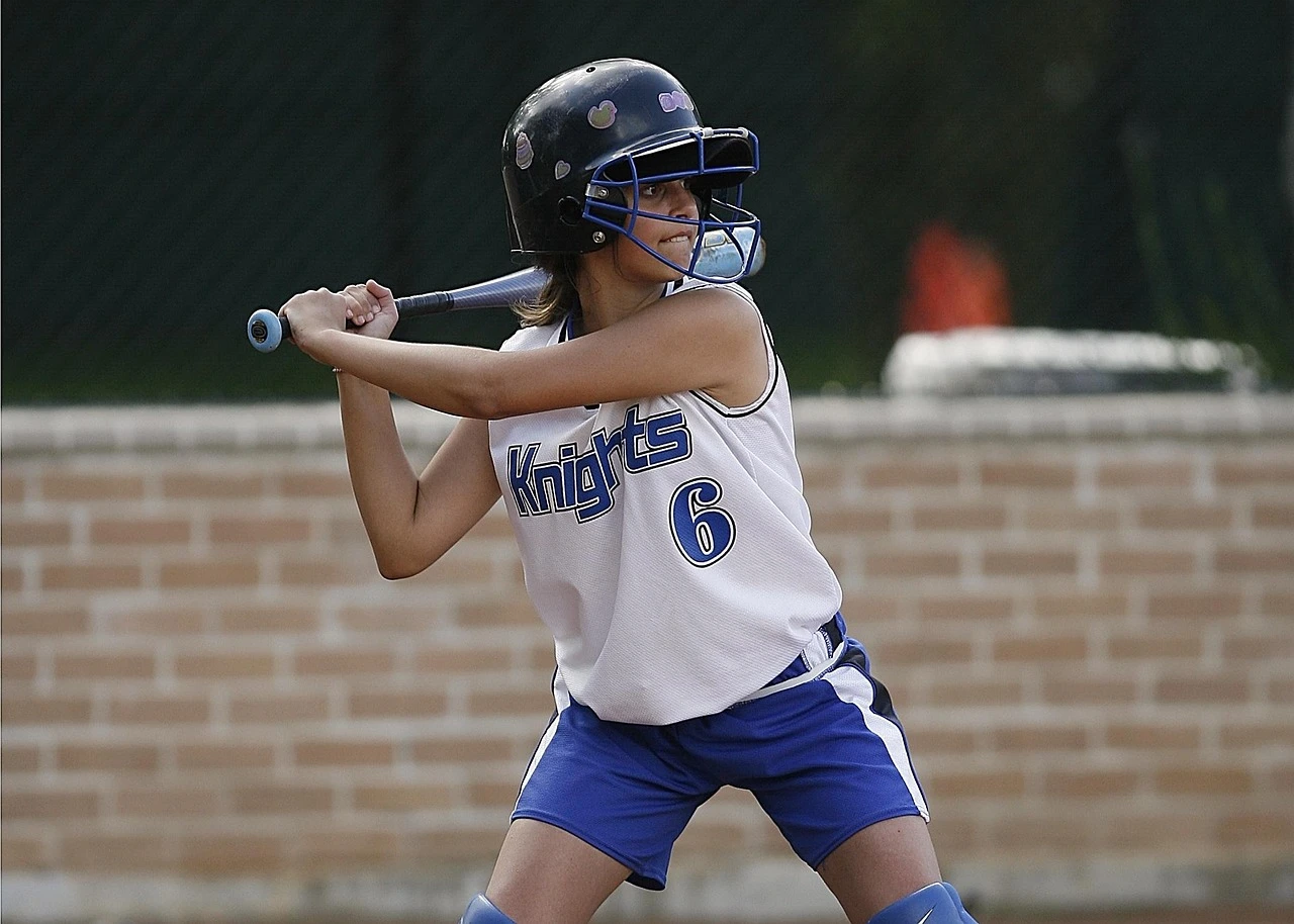 Slo-pitch softball players compete on a green community diamond on a summer afternoon.