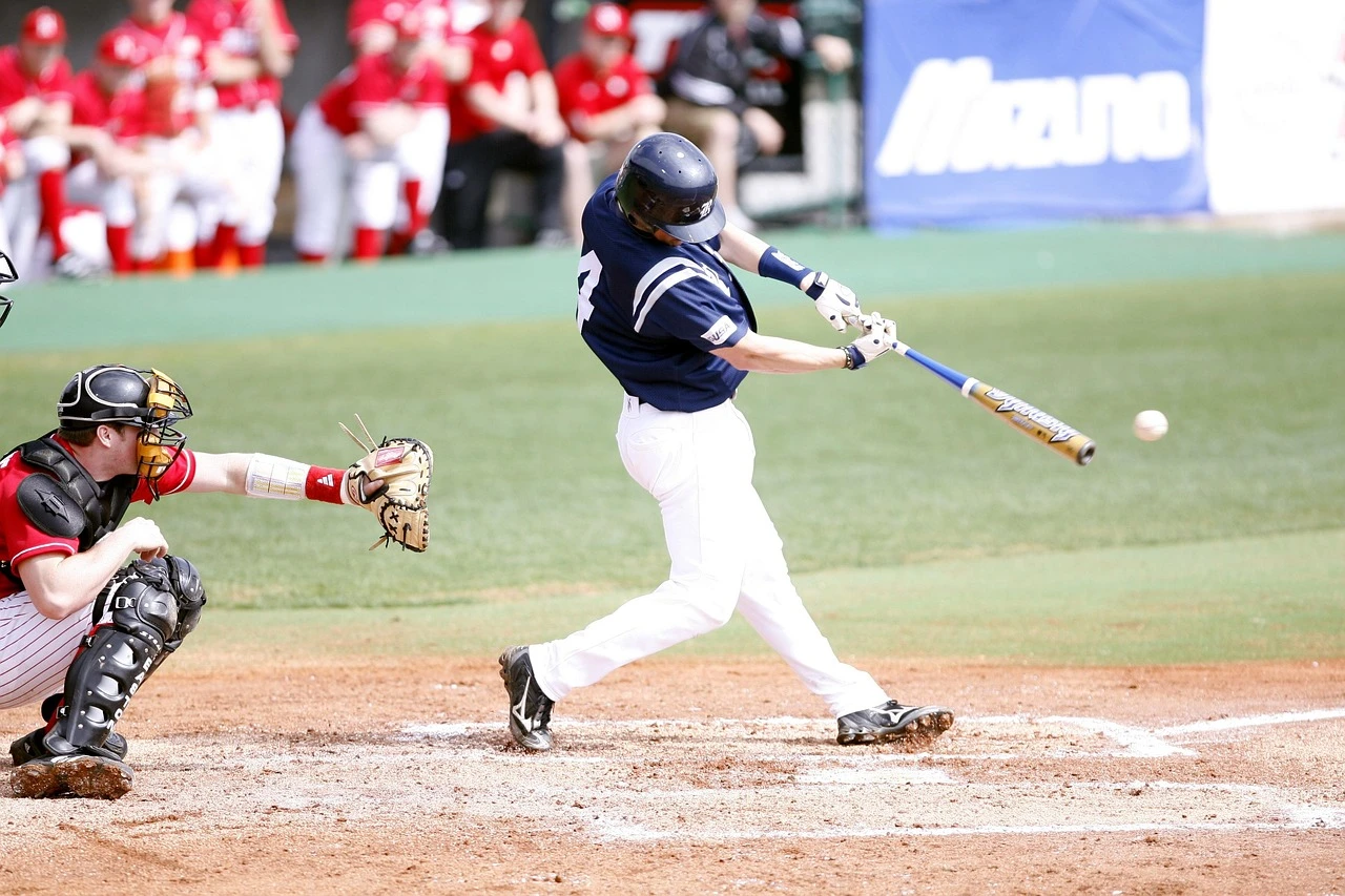 A batter in a plain uniform at home plate during an amateur baseball game at a small-town diamond.
