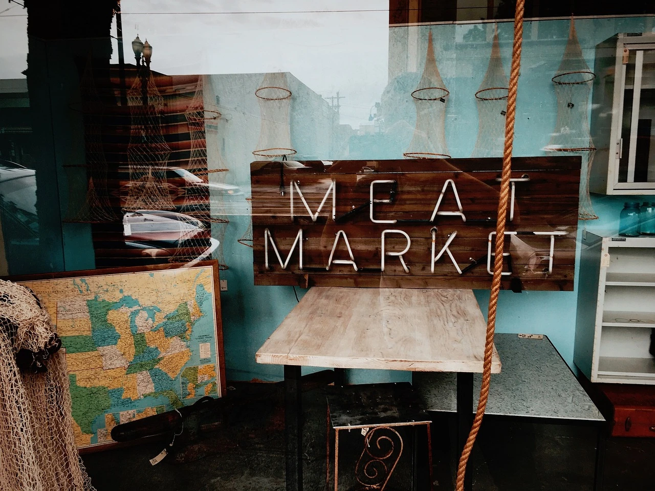 A storefront of a retail meat shop in a suburban plaza at dusk.
