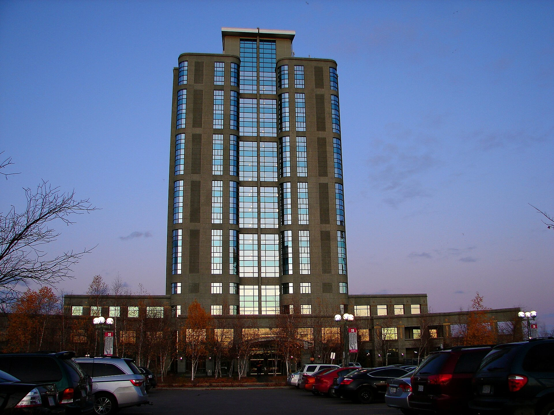 A hotel spa entrance in Ottawa at dusk with autumn leaves and parked cars.