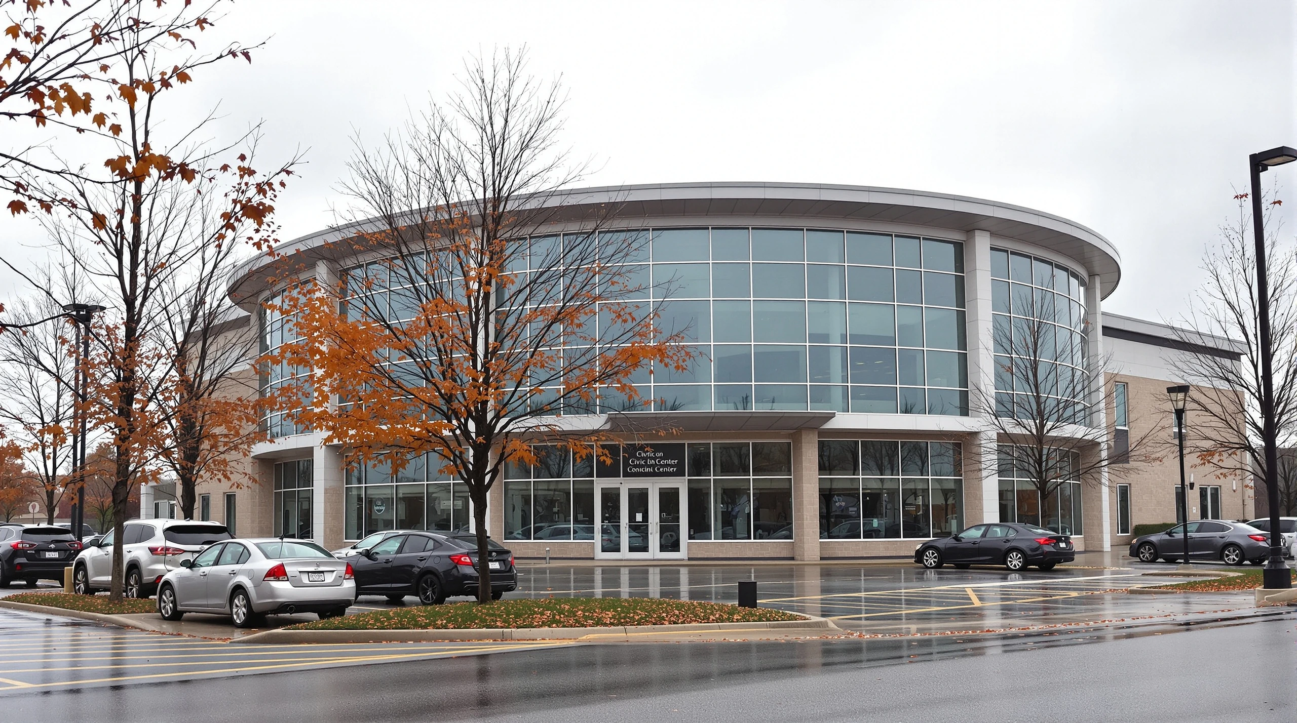 A municipal civic centre building in Markham under an overcast autumn sky, surrounded by trees with orange leaves and parked cars.