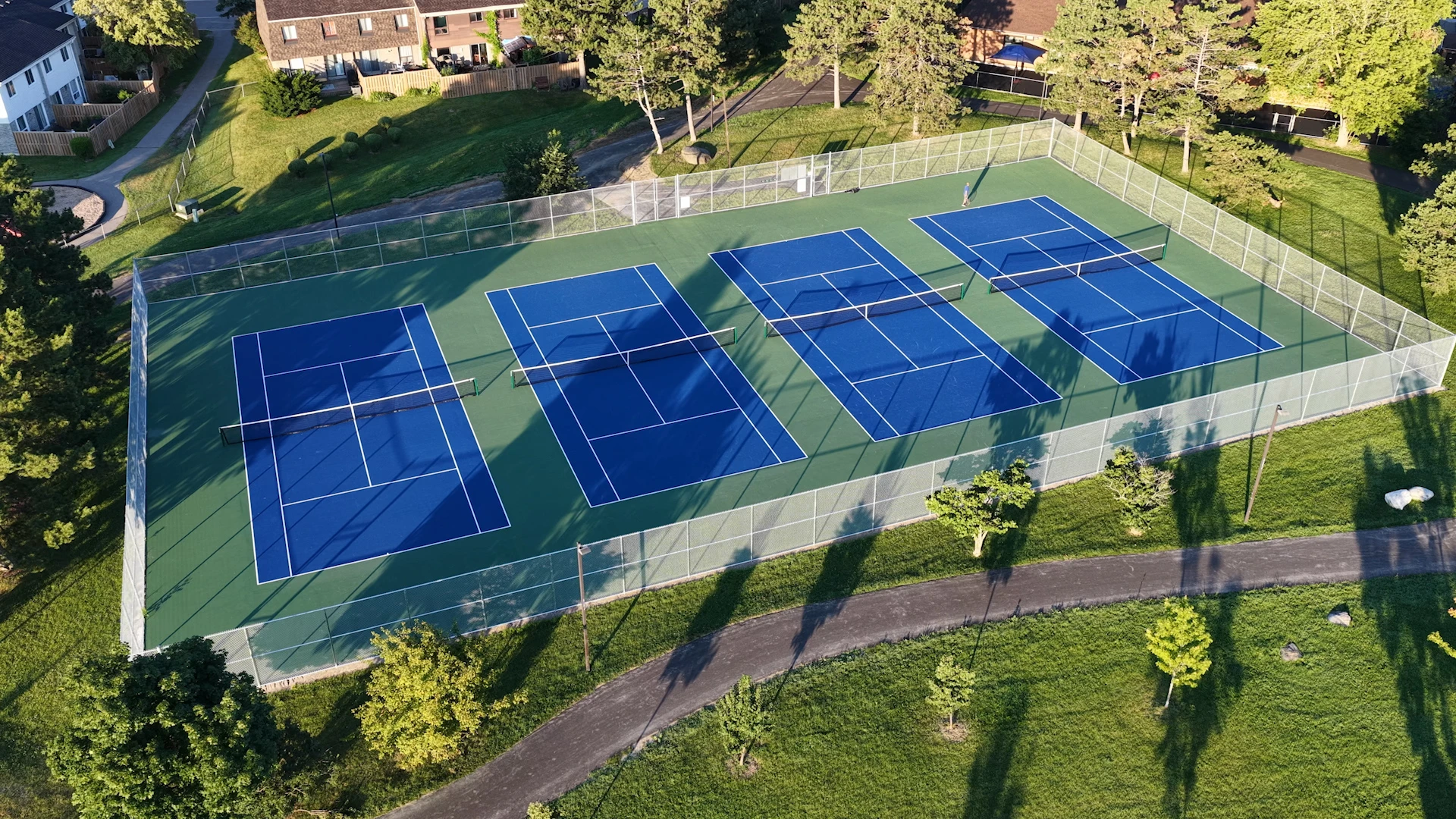 Illustration of outdoor tennis courts with a net and green summer trees in a suburban park.