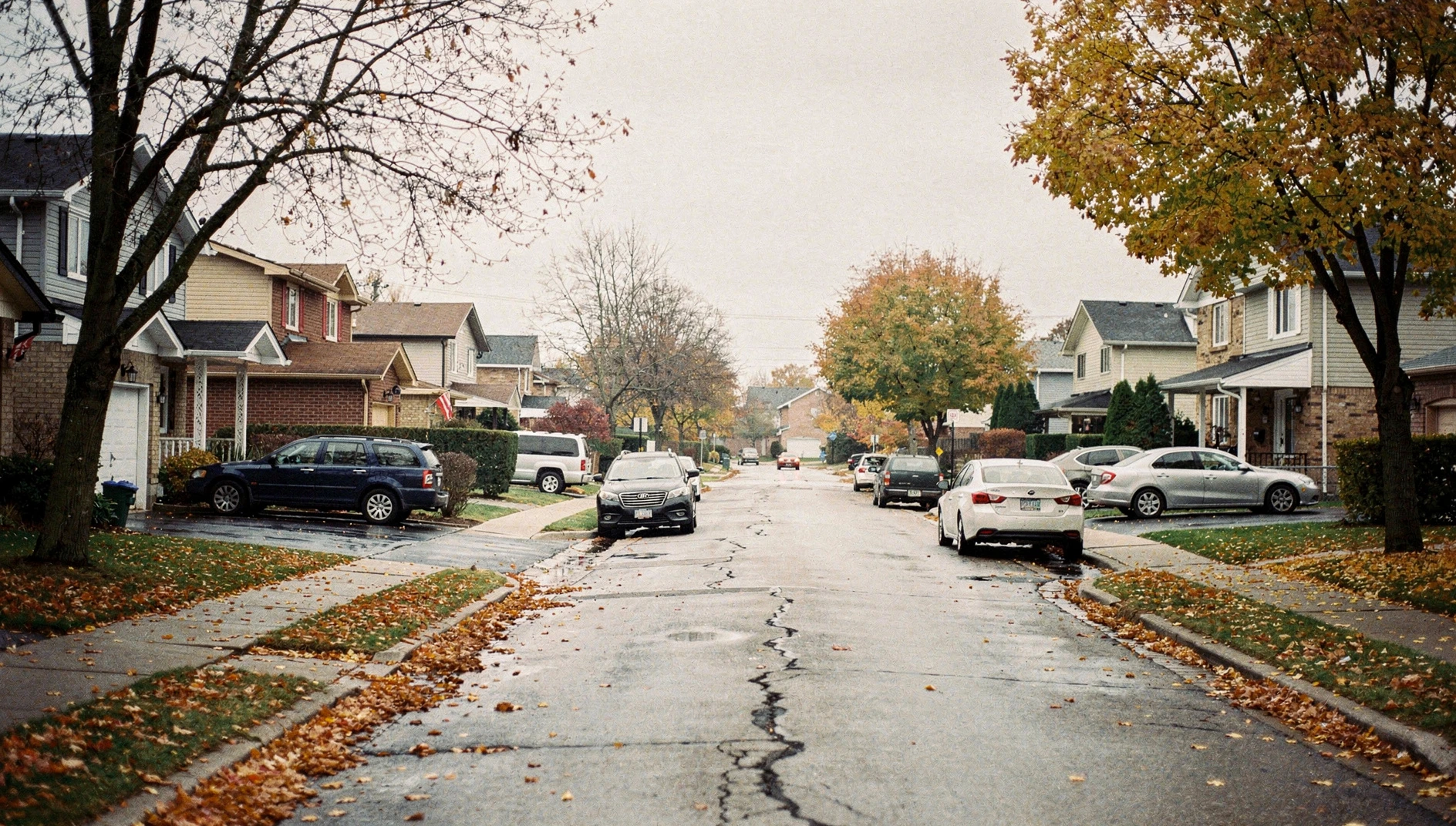 A quiet residential street in Pickering, Ontario, during a cloudy autumn afternoon with fallen leaves on the ground.