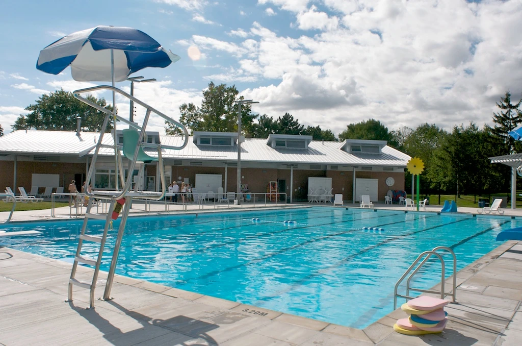 Illustration of an outdoor municipal swimming pool with a concrete deck and summer trees.