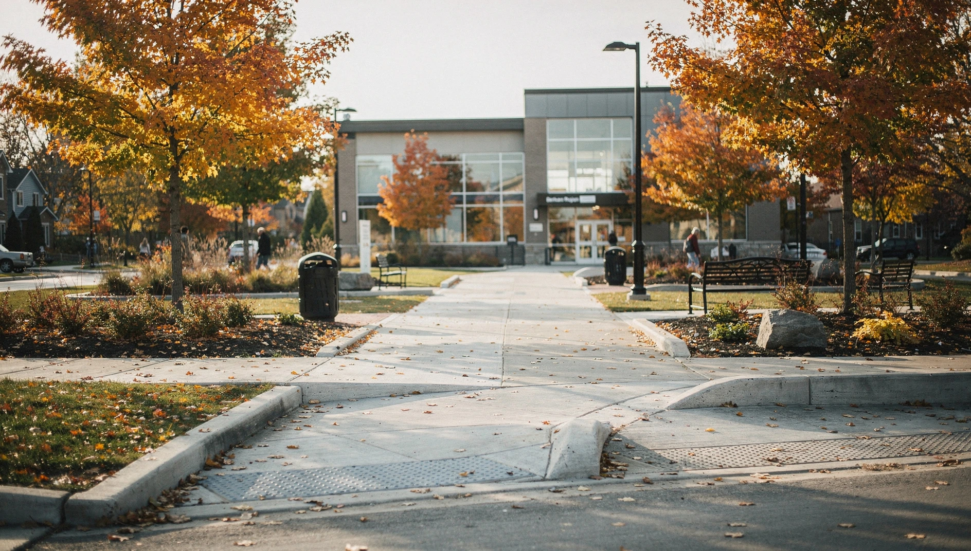 A wide-angle shot of a modern public plaza in Durham Region with accessible ramps and paved walking paths under autumn trees.