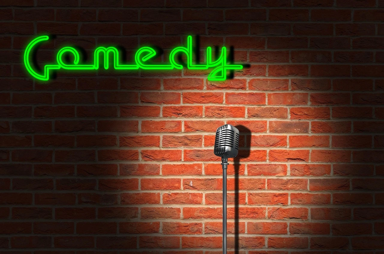 An illustration of a bright stage with professional lighting and microphones in a darkened theatre.