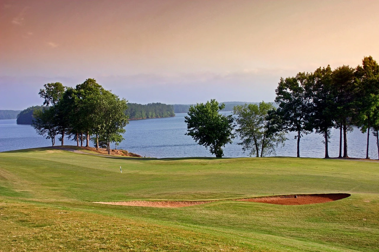 A green golf course fairway with mature trees under morning light.